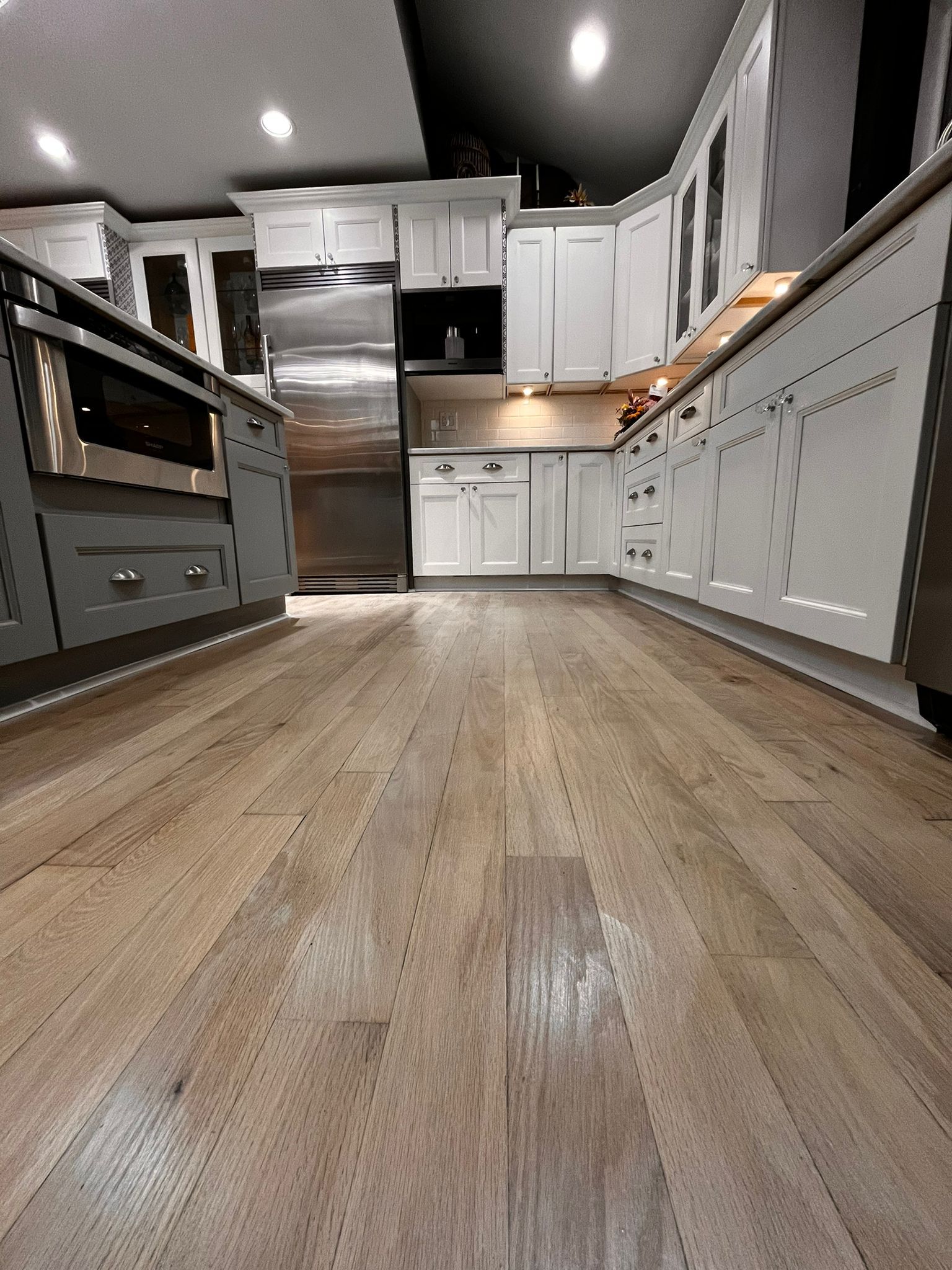 Kitchen with light wood floor, white cabinets, and stainless steel appliances.