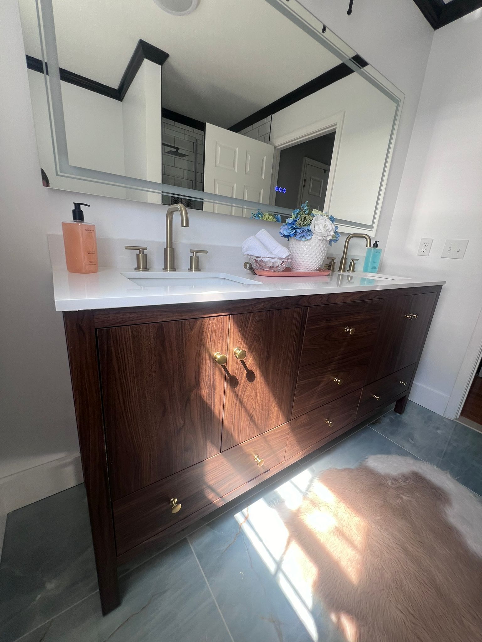 Wooden vanity with a white countertop and large mirror in a bathroom.