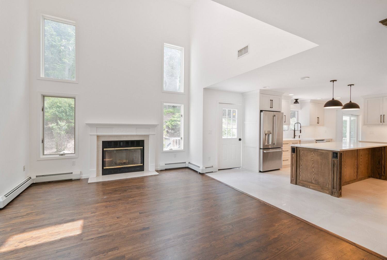 Living room with fireplace, hardwood floor, and open kitchen with island.