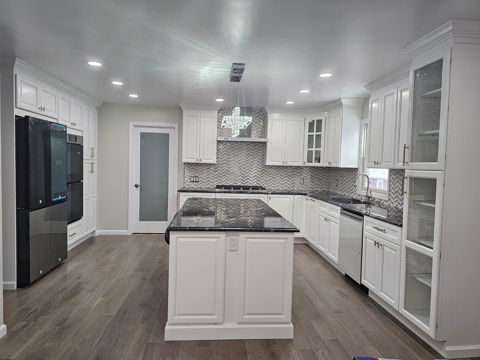 White kitchen with a black granite island and matching appliances.