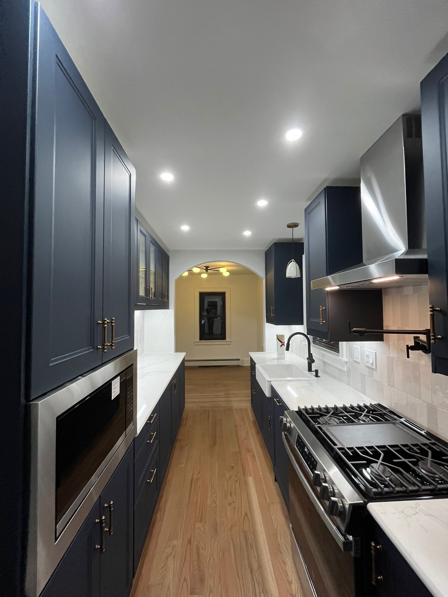 Navy blue kitchen with white countertops and stainless steel appliances.