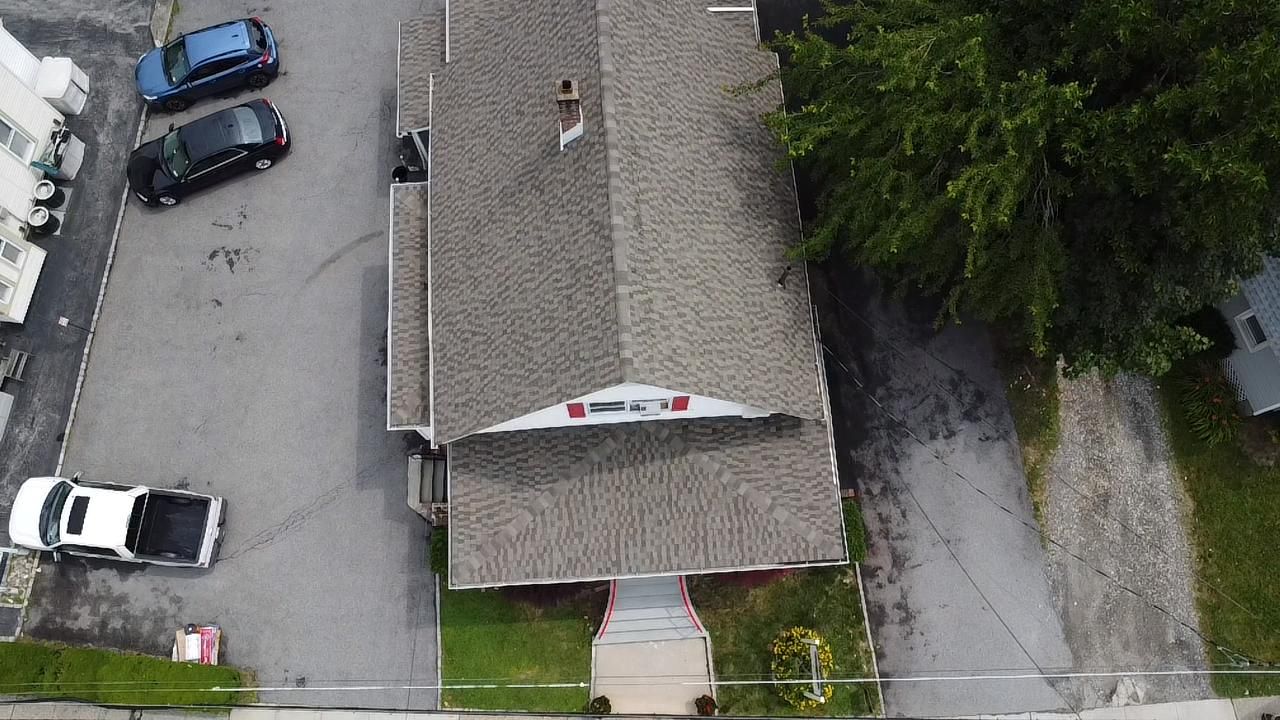 Overhead view of a building with cars parked in front, a tree to the right, and a walkway to the entrance.