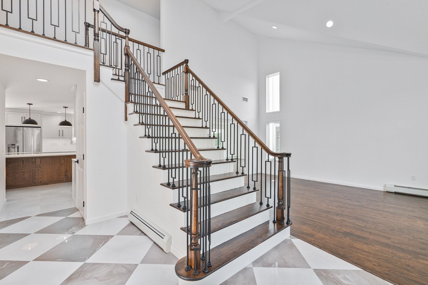 Staircase in a modern home with dark wood handrails, leading to a loft. Checked floor in entry.