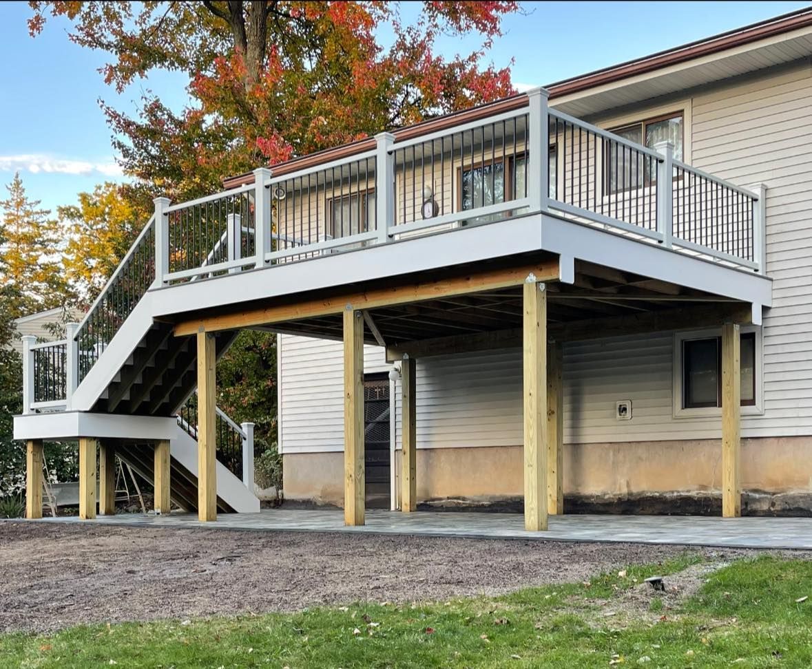 Deck built onto a house with stairs. The deck is gray and has black railings.