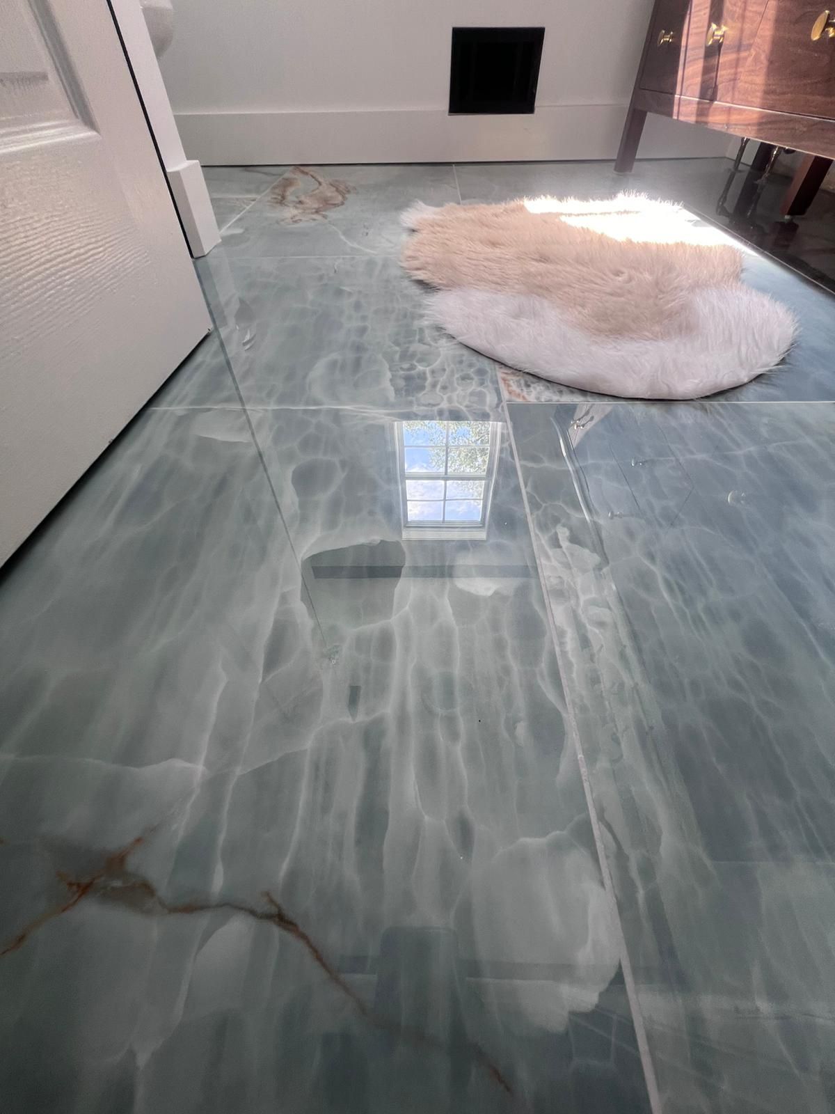 Blue and white stone tile floor with a small rug, near a door and window.