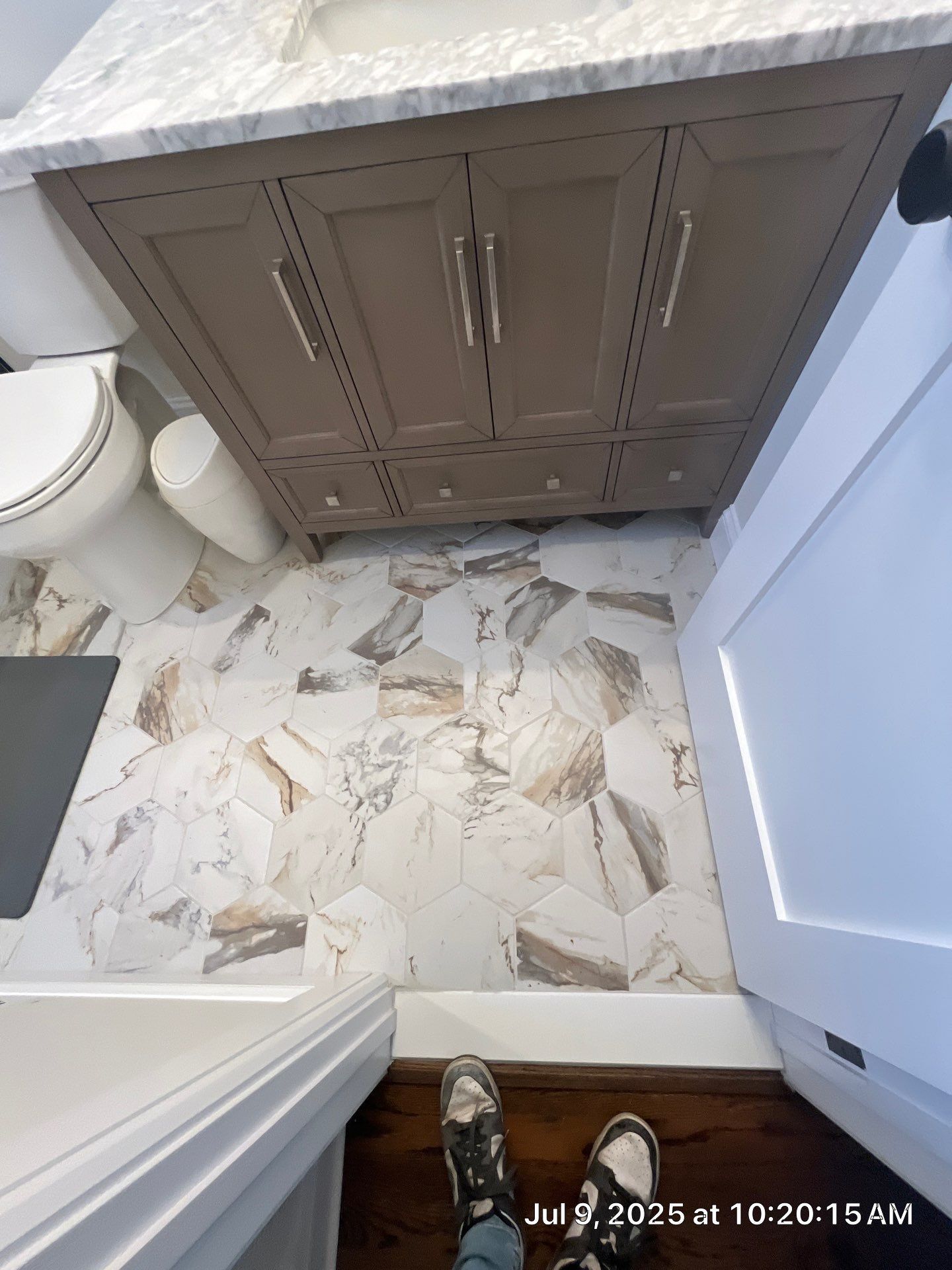 Bathroom with gray vanity, patterned floor tiles, and white toilet.