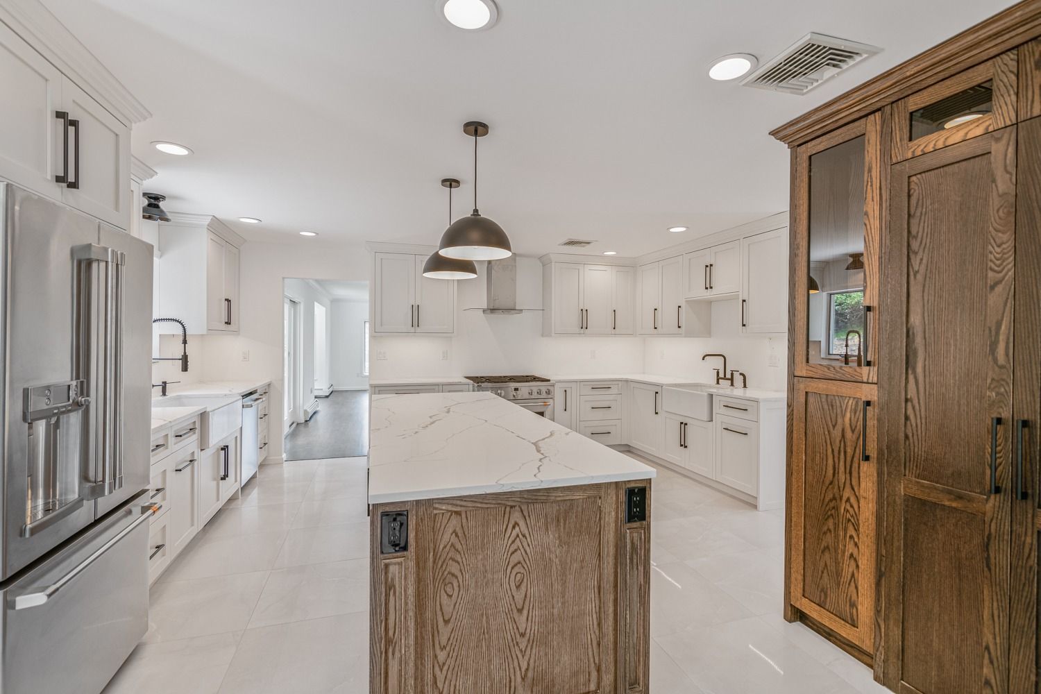 Modern kitchen with white cabinets, stainless steel appliances, wooden island, and pantry.