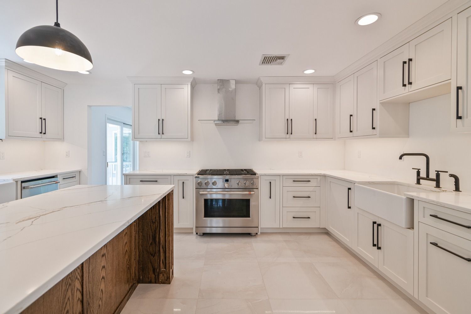 Bright white kitchen with stainless steel appliances, white cabinets, and a large island.