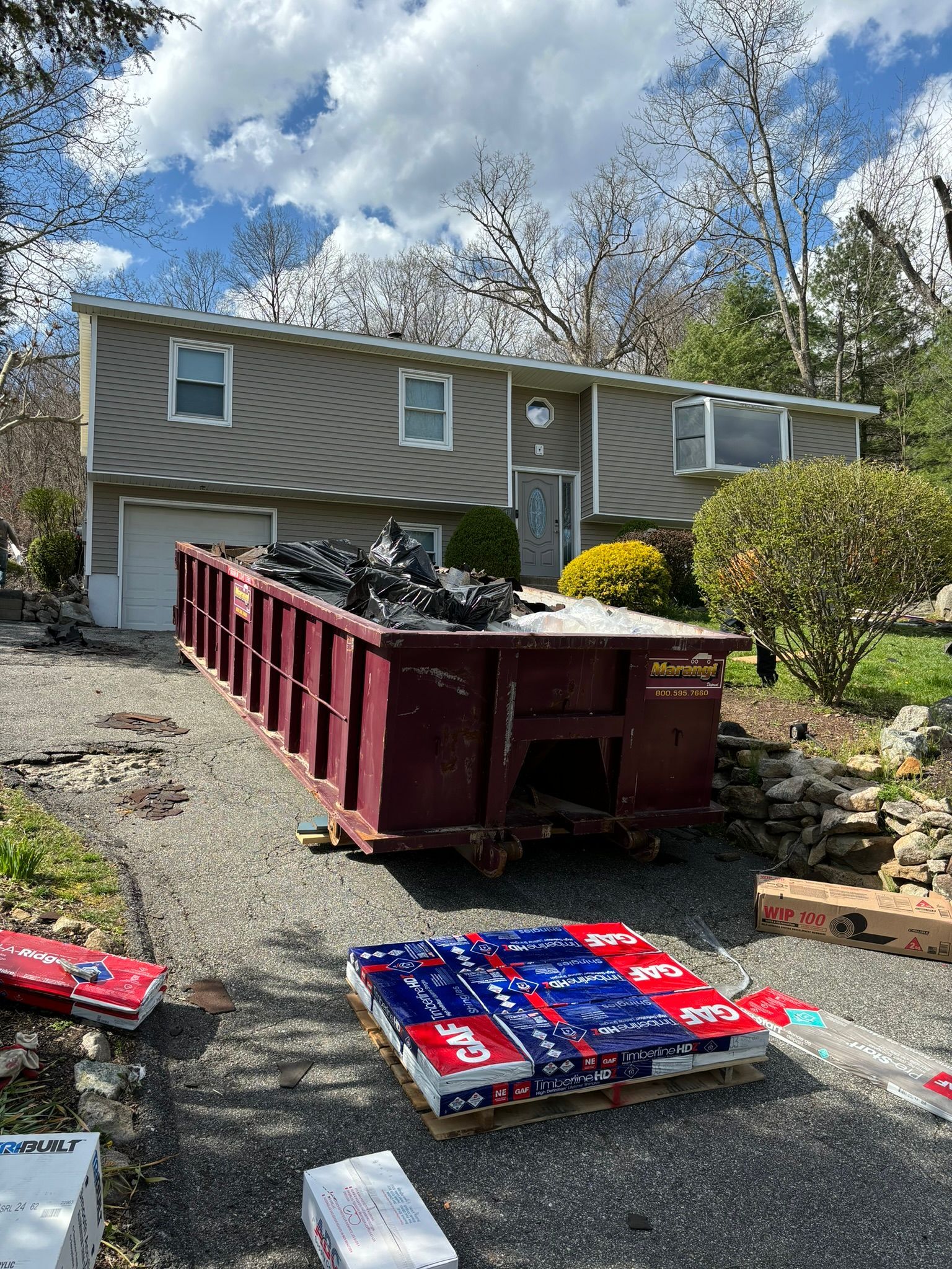 A two-story house with a dumpster in the driveway, construction materials are visible.