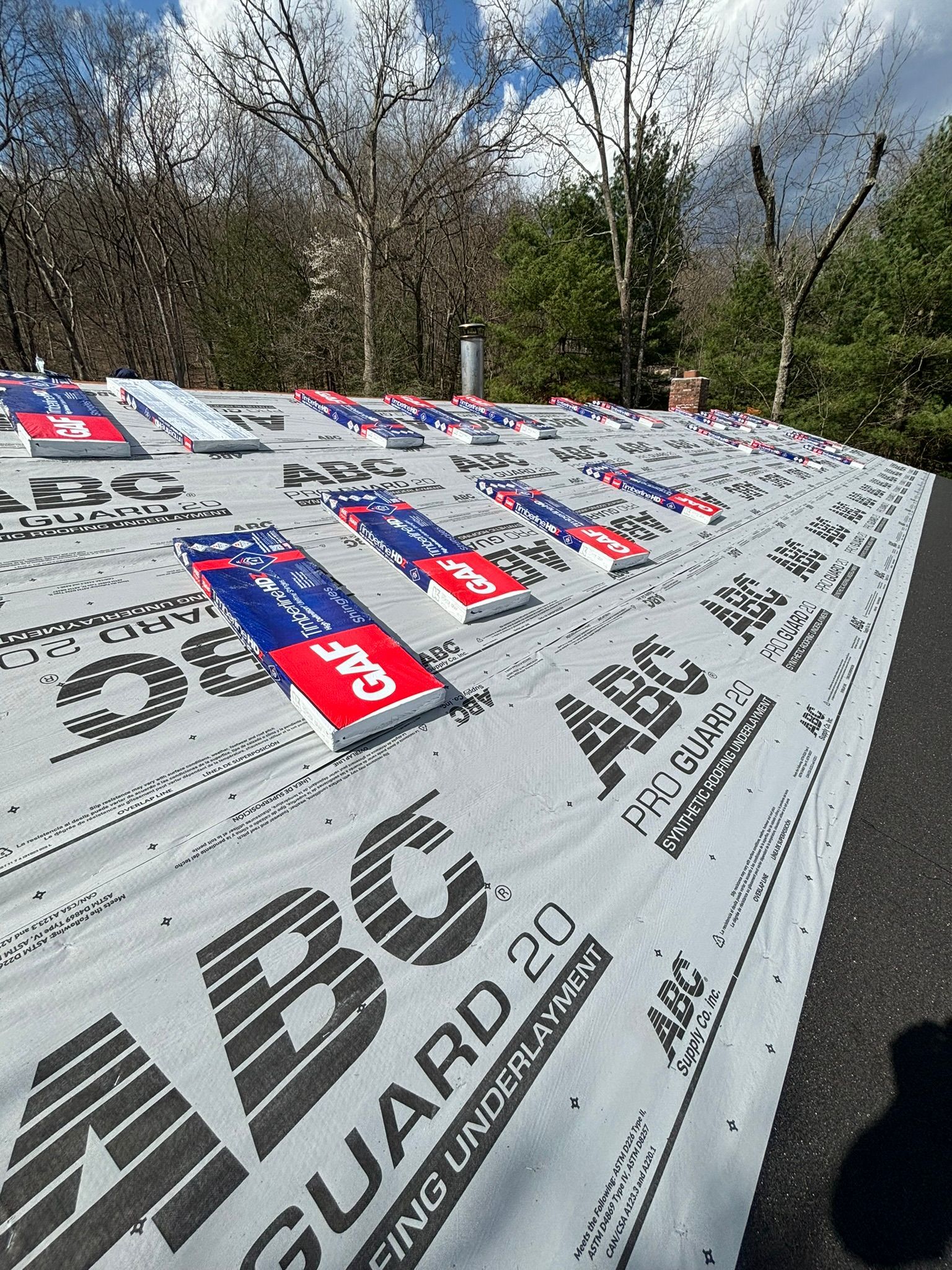 Roof underlayment with colorful tabs, viewed outdoors under a blue sky.