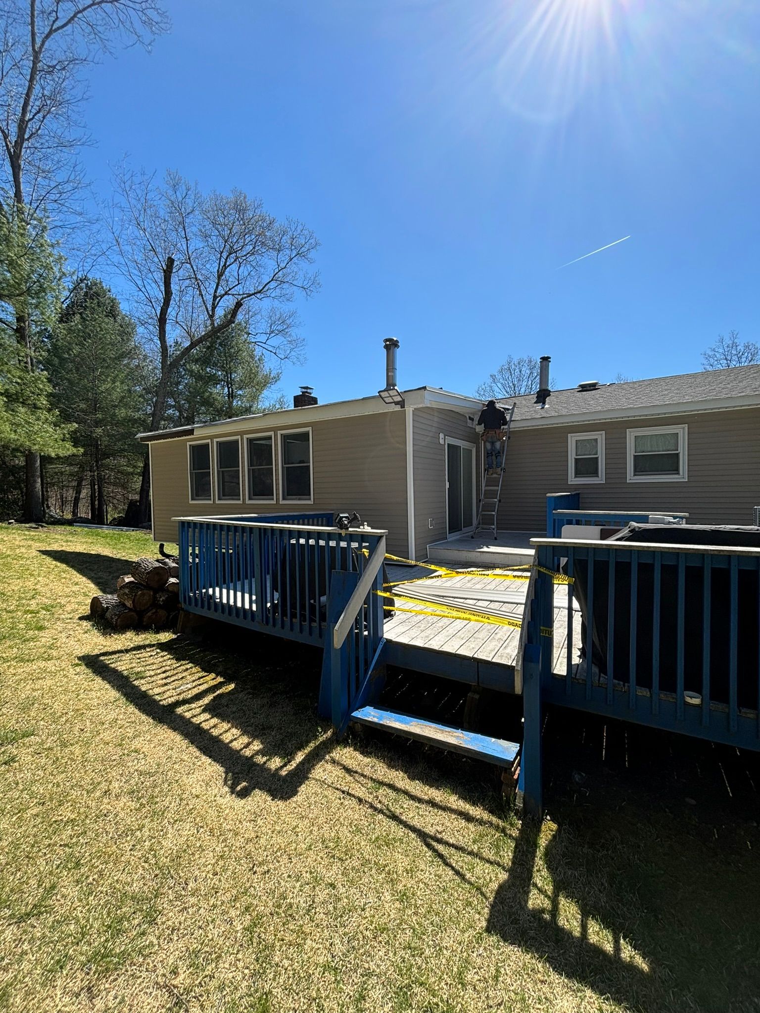 Backyard with a wooden deck and house; a ladder leans against the roof.