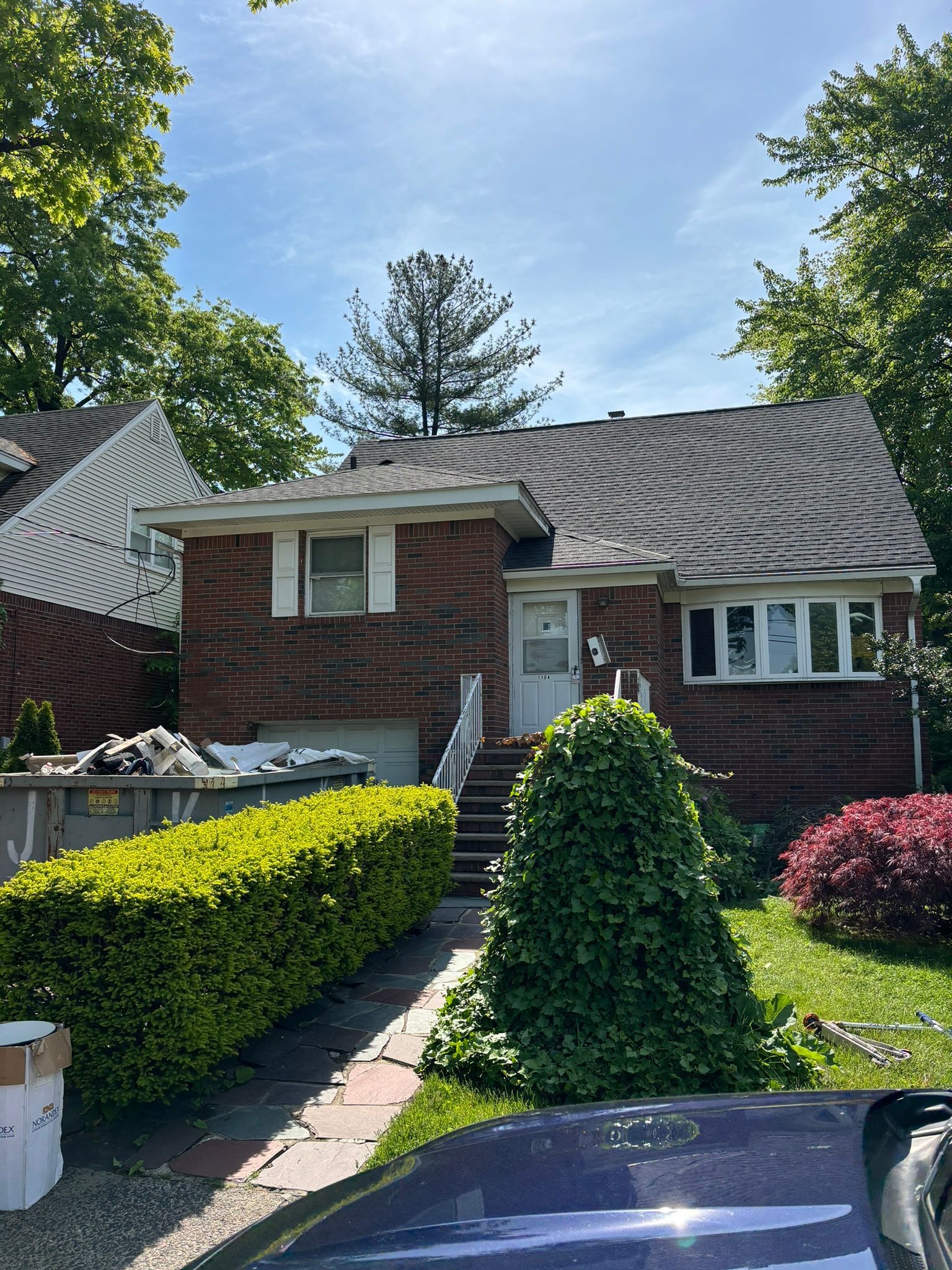 Brick house with a walkway and small front yard, sunny day.