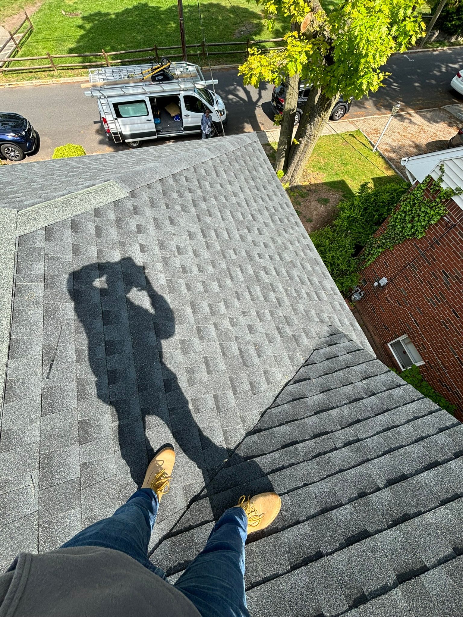 Person on a roof with their shadow, a white van parked on the street below.