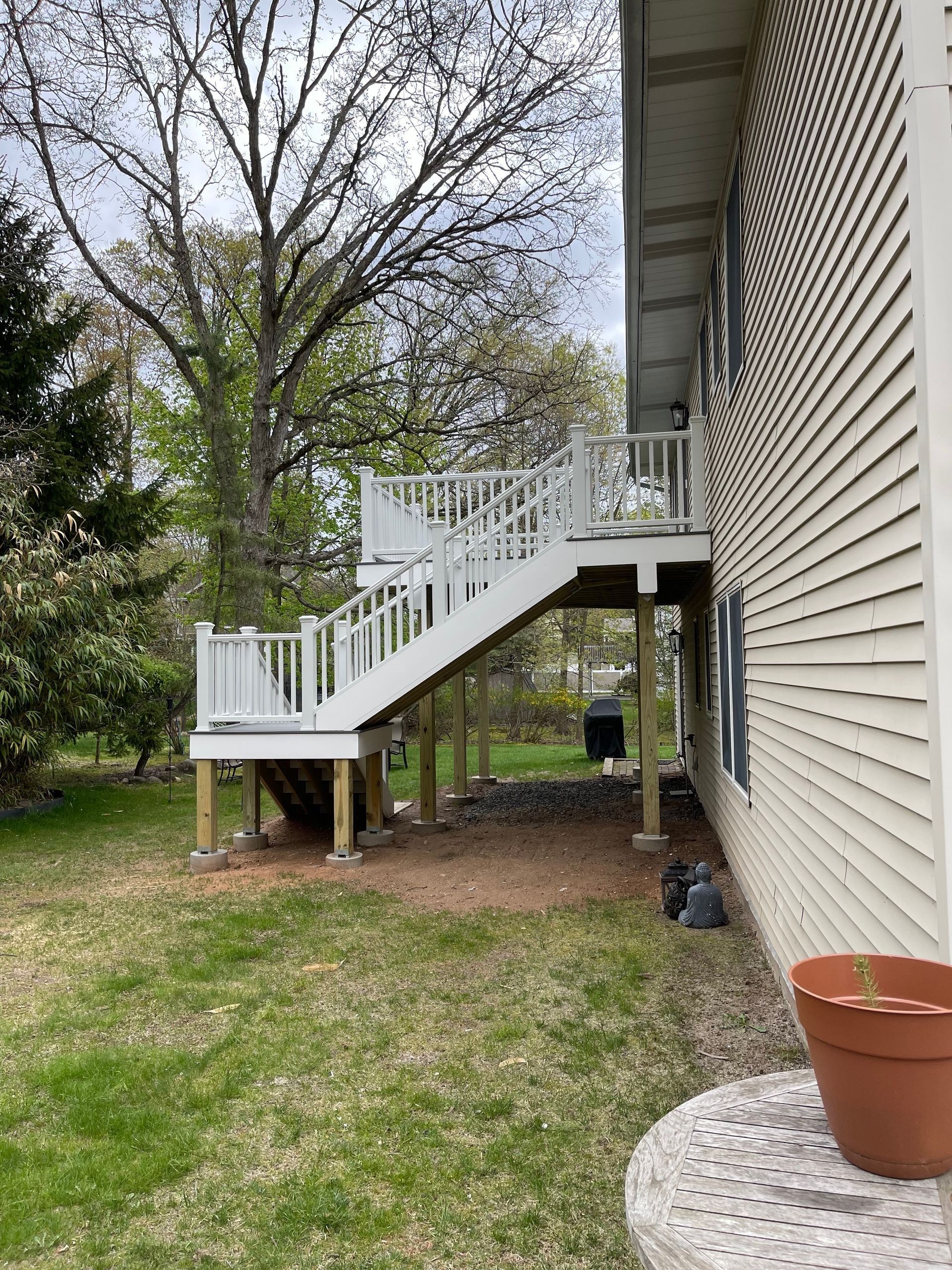 White deck with stairs descending to the yard, beside a beige house.