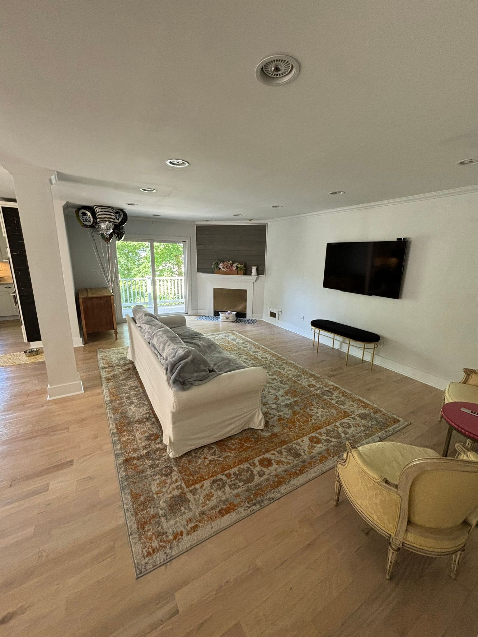 Living room with sofa on patterned rug, fireplace, and TV on wall.