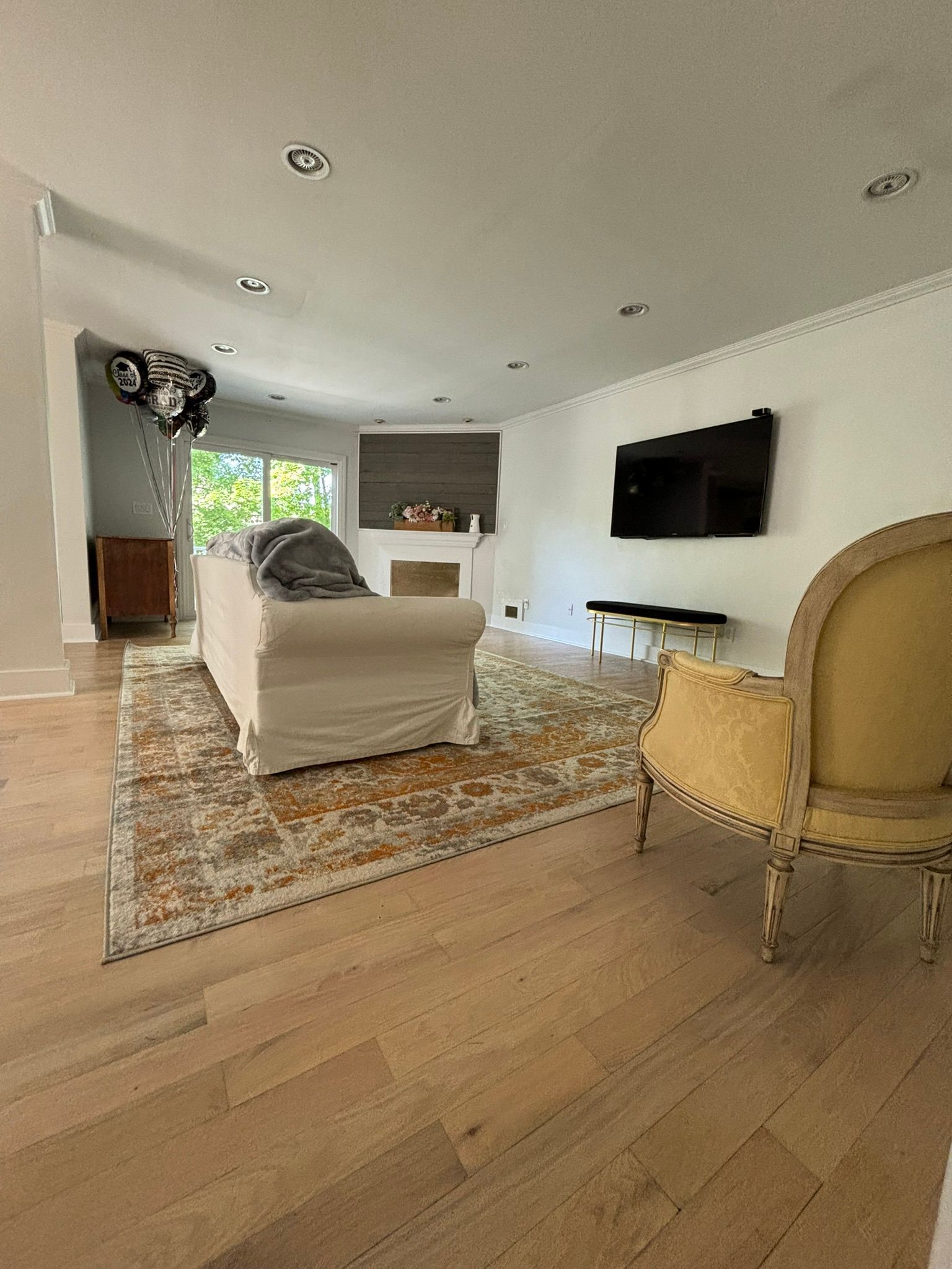 Living room with a white couch, yellow chair, TV, and a fireplace.