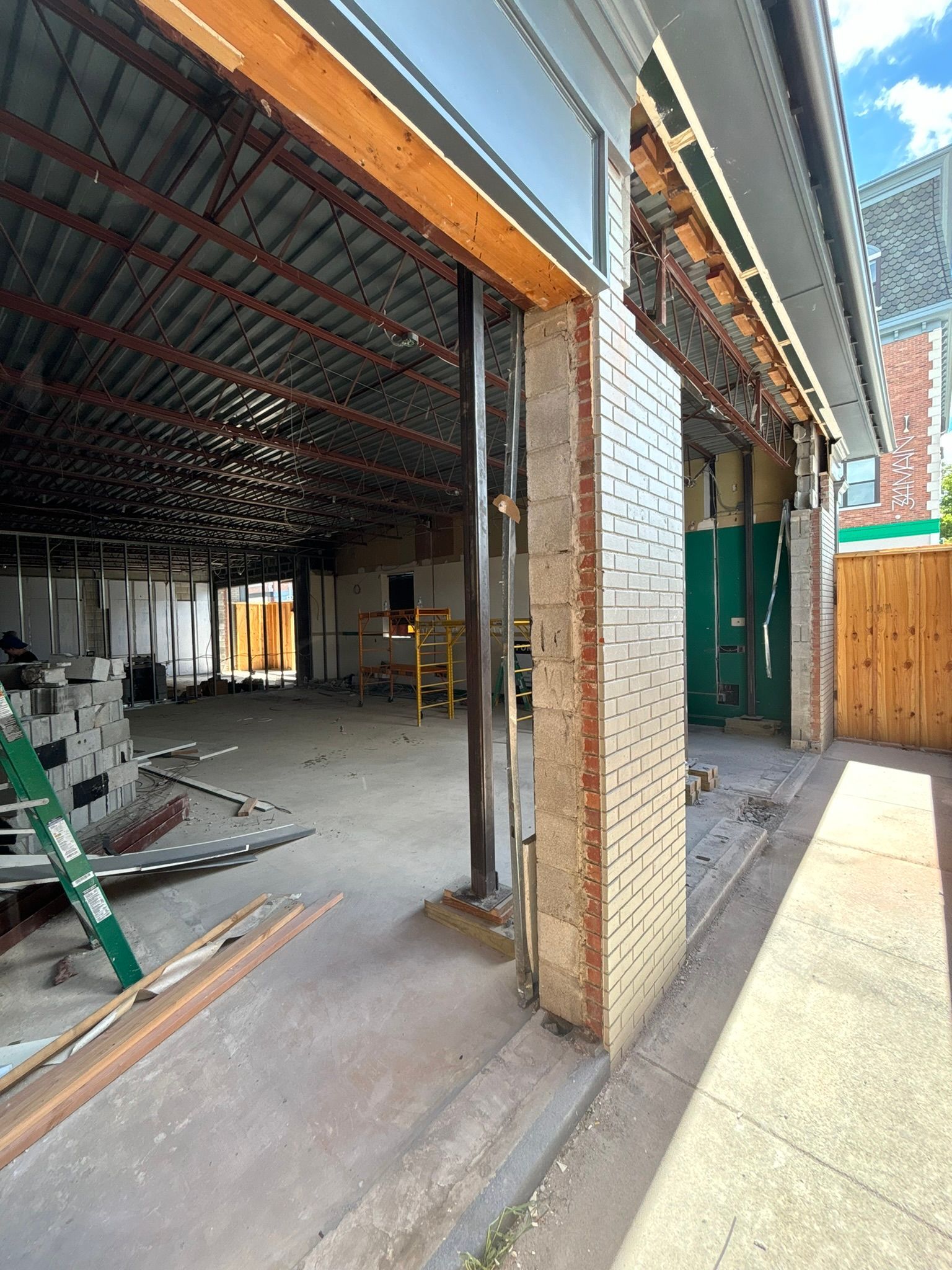 Construction site: Brick wall, exposed beams, concrete floor, open doorway.