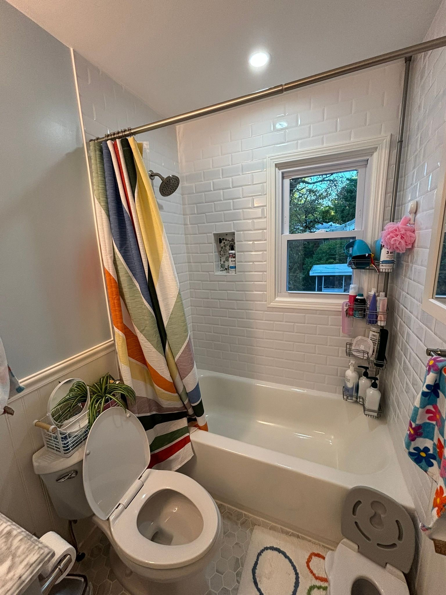 Bathroom with white subway tile, shower curtain, and toilet.