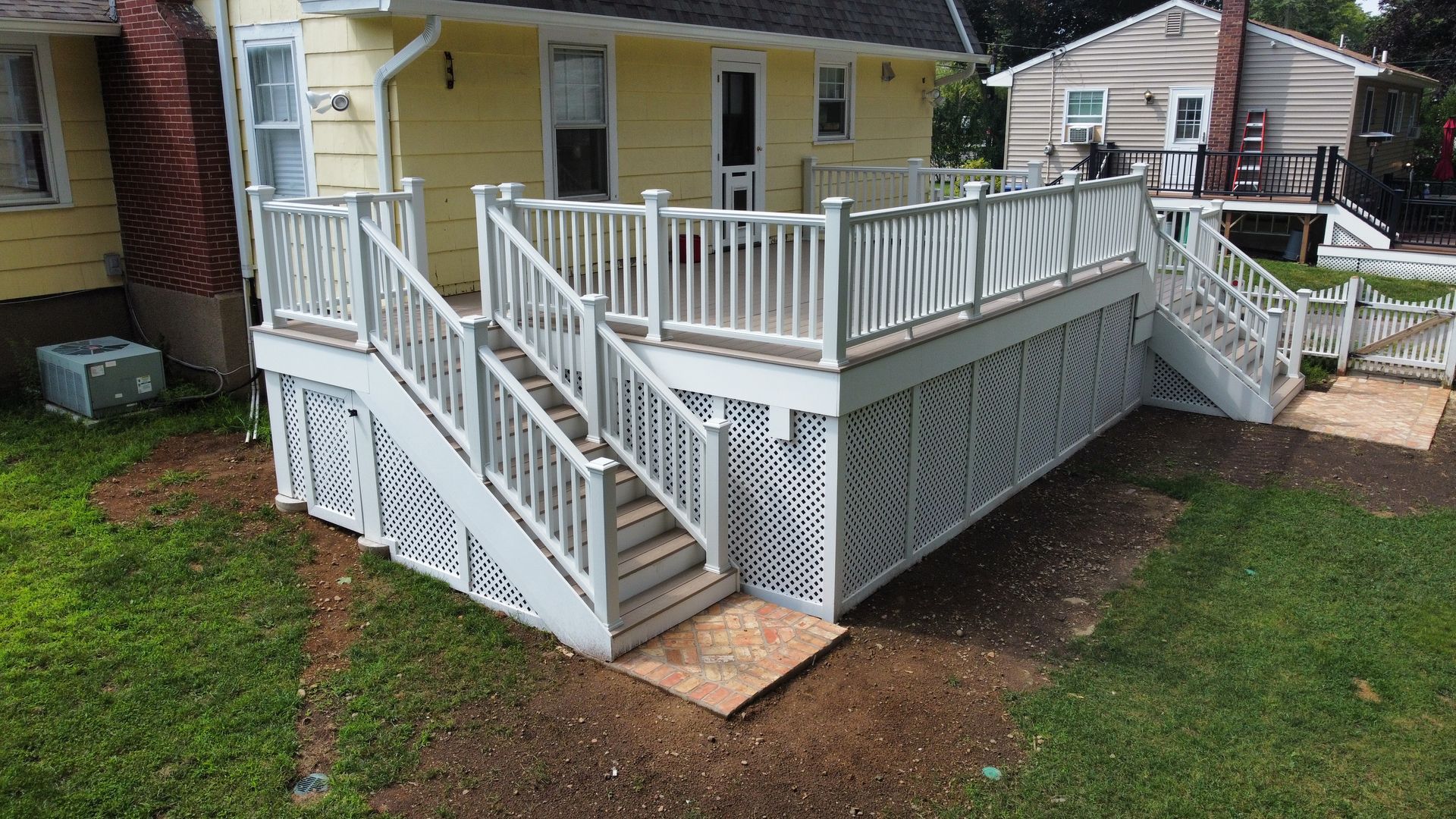 White deck with lattice skirting and stairs leading to ground level.