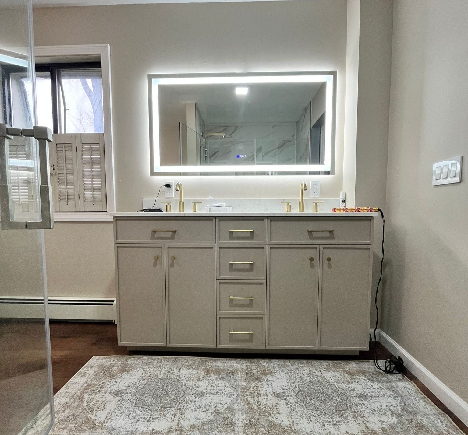 Bathroom with a double vanity, lighted mirror, and area rug.