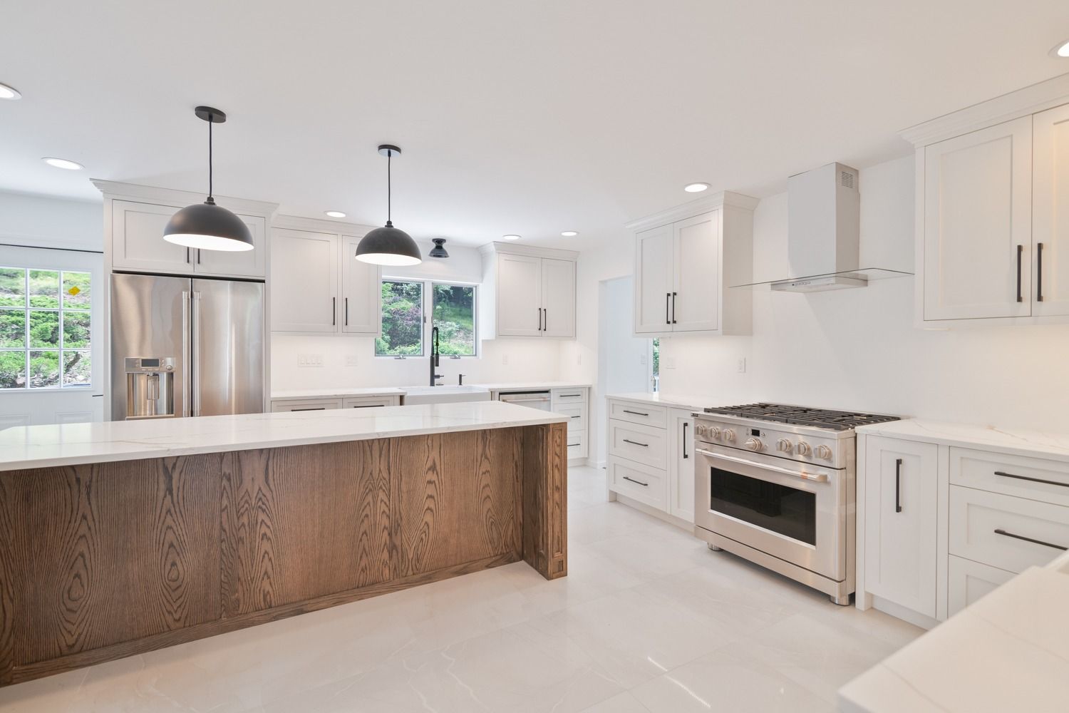 Modern white kitchen with wooden island and stainless steel appliances.