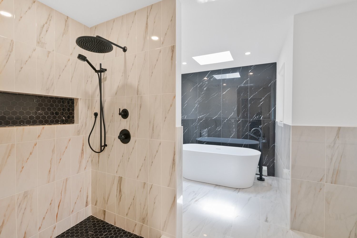 Modern bathroom with shower and freestanding tub; black shower fixtures, marble and black tile accents.
