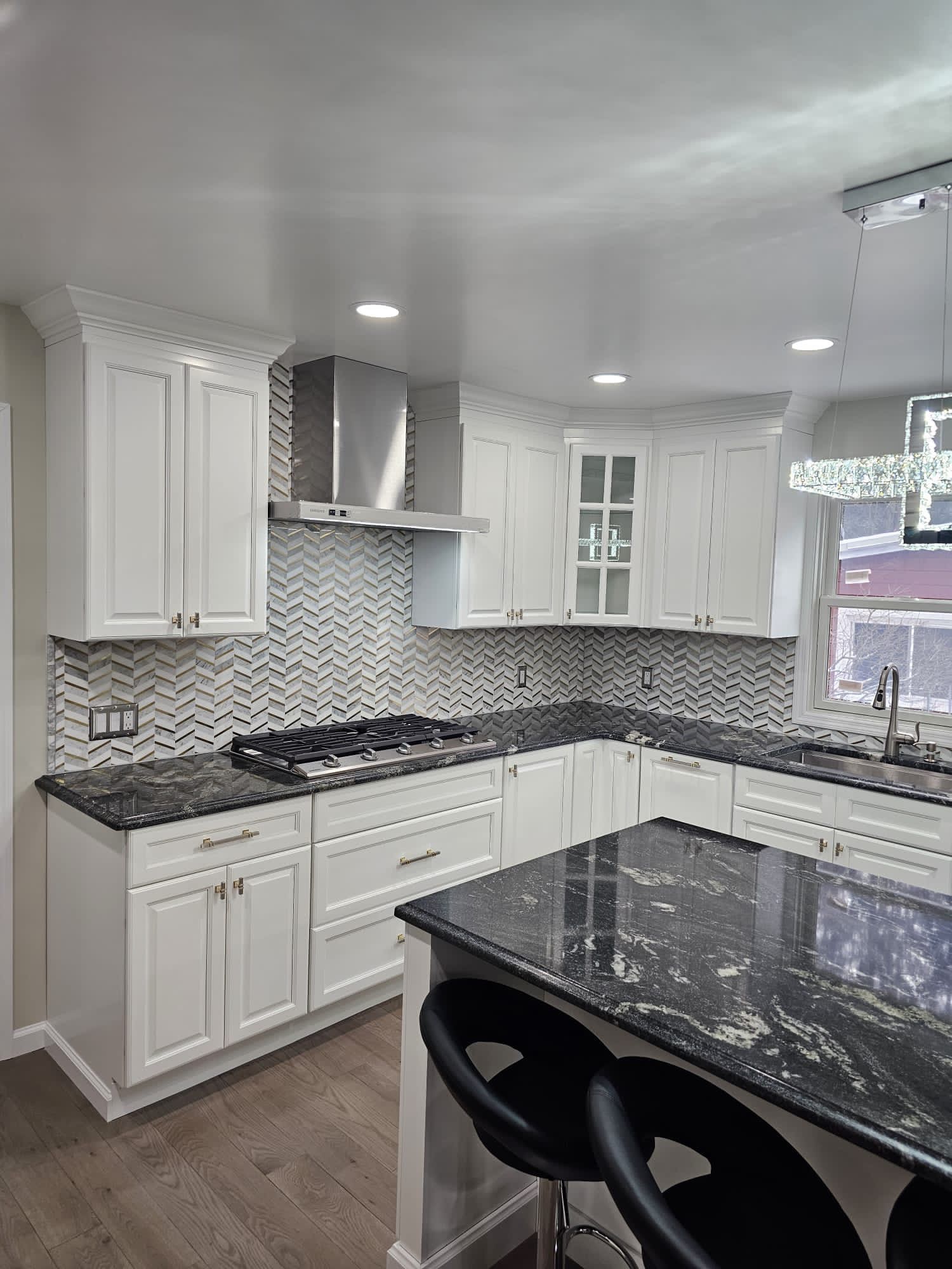 White kitchen with dark granite countertops and a patterned backsplash.
