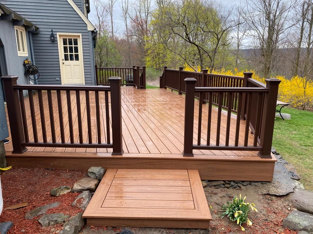 Wooden deck with railing in backyard setting; dark brown and tan color.