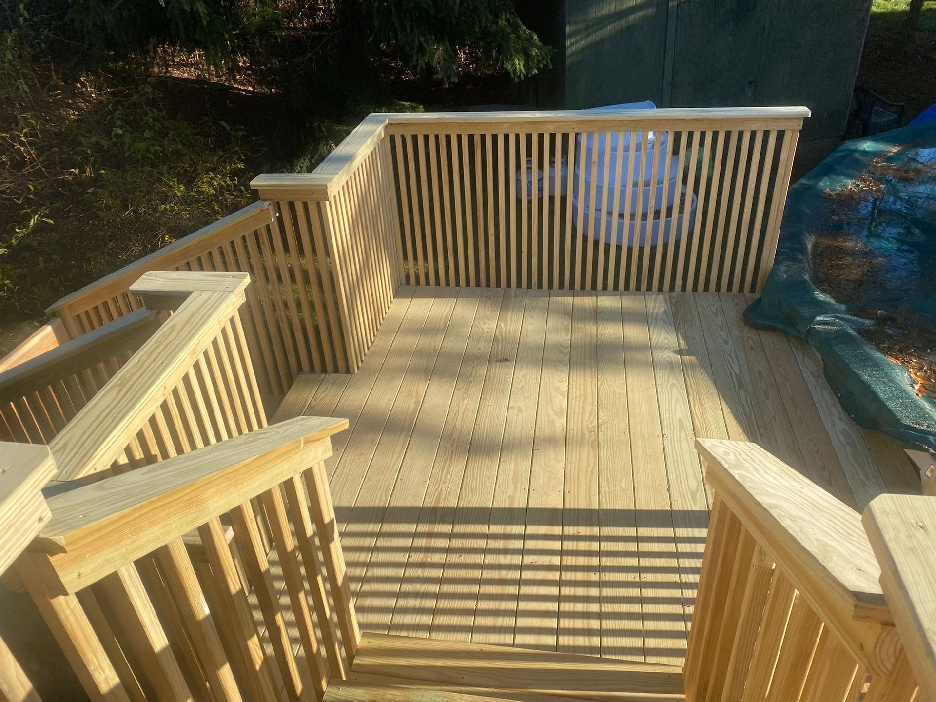 Wooden deck with railings and vertical slat fencing, outdoors.