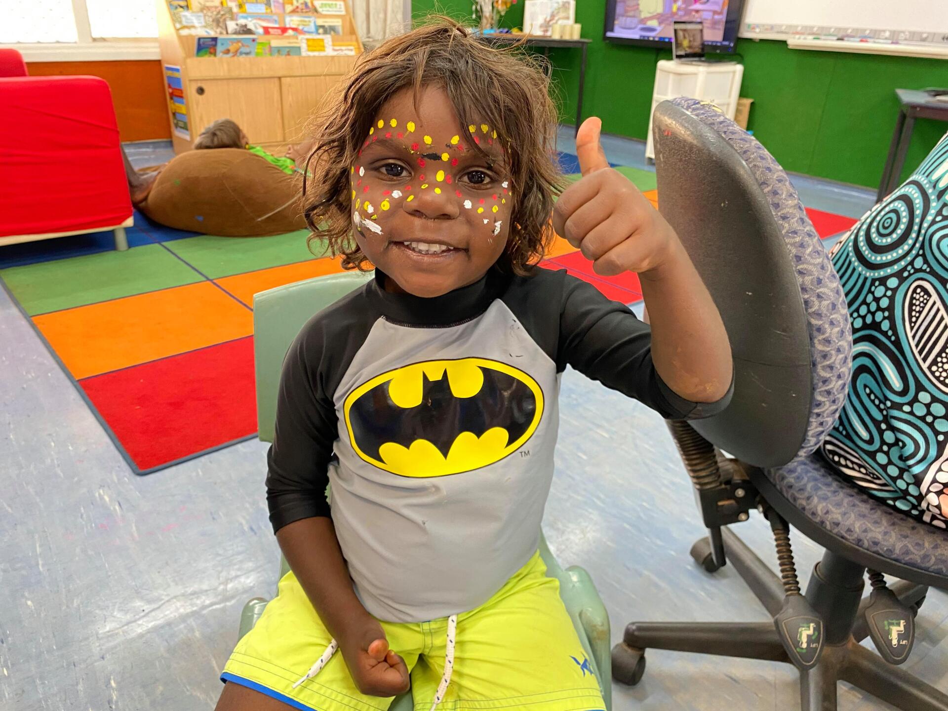 Students painted face putting thumbs up