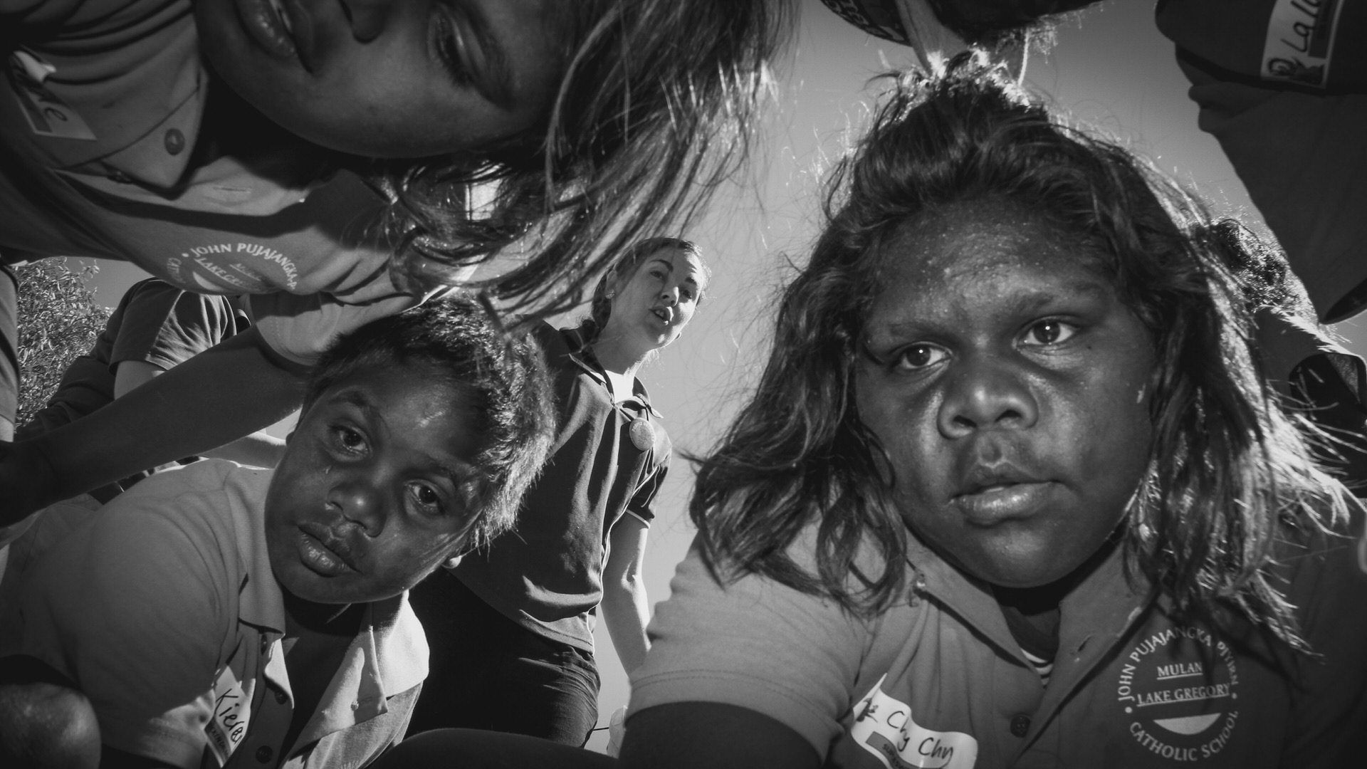 Teacher and students from the JPP School looking down at the ground