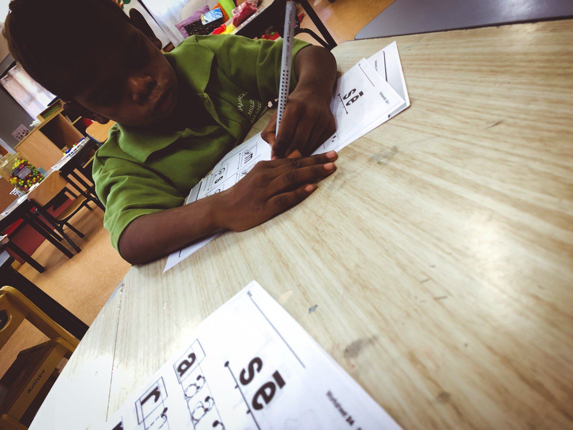 JPP School student writing on paper at his desk