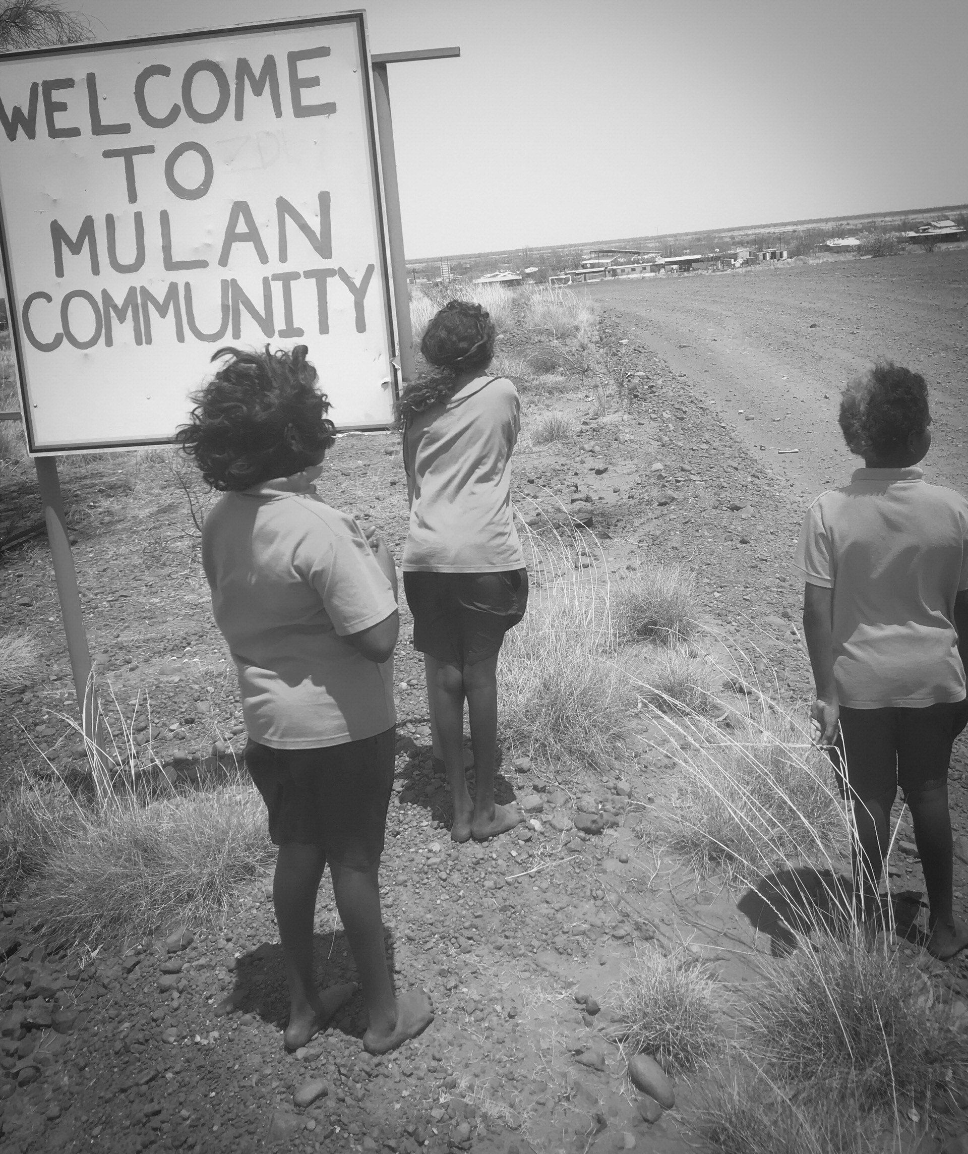 Three JPP School student girls standing at the 'welcome to Mulan' sign