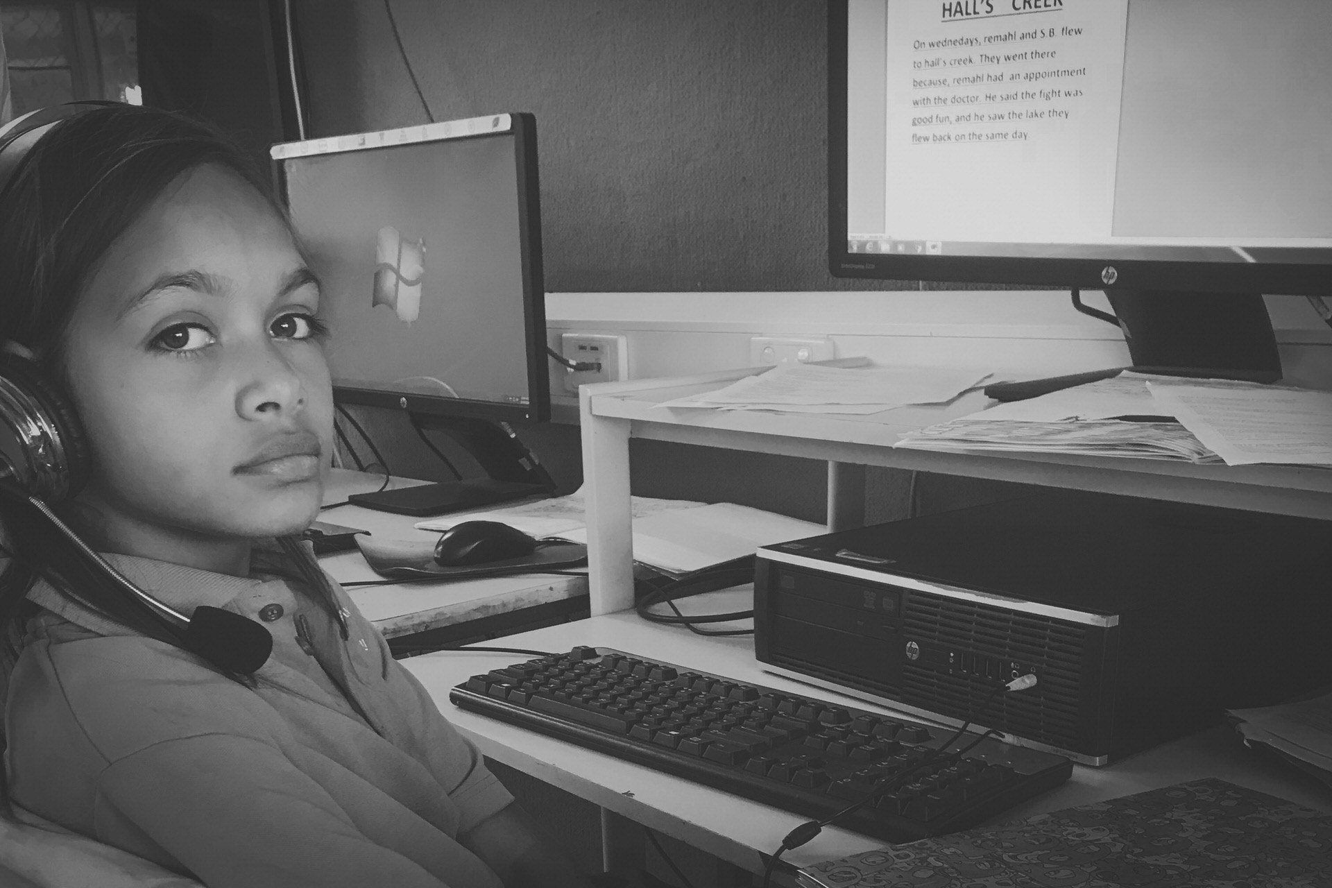 JPP School student sitting at a computer desk wearing headphones