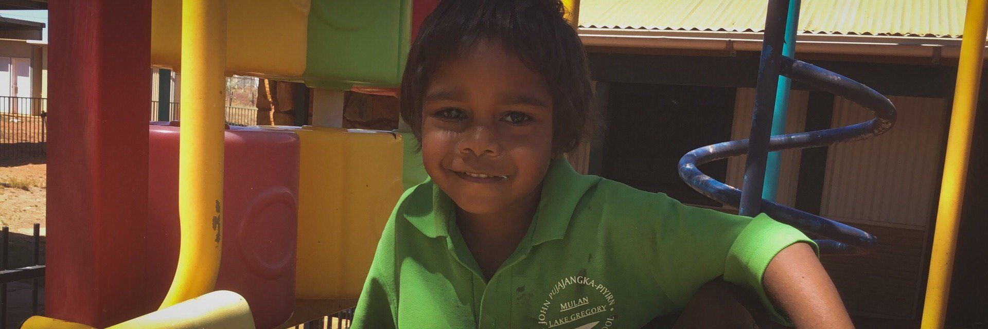 JPP School student smiling at the camera before sliuding down a slide