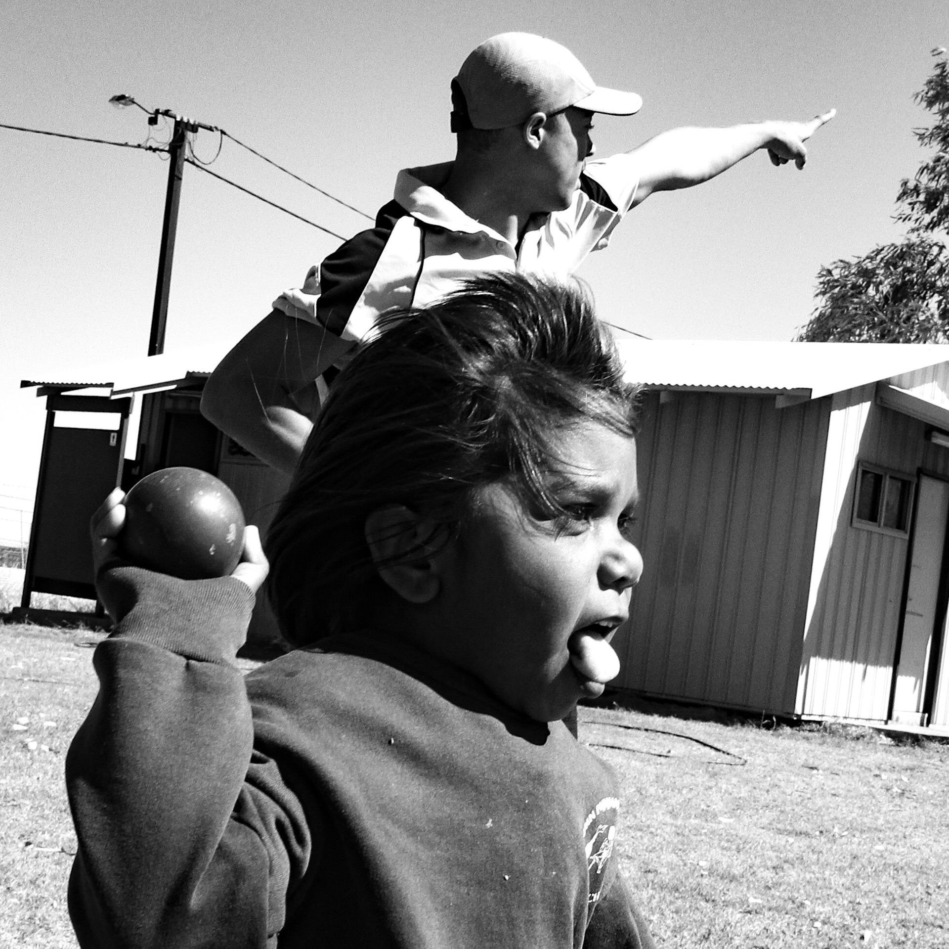 Very young JPP School student throwing a ball with her tounge out