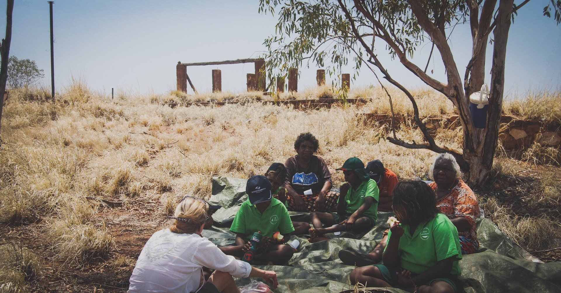 JPP School students sitting in long grass with elders and a teacher