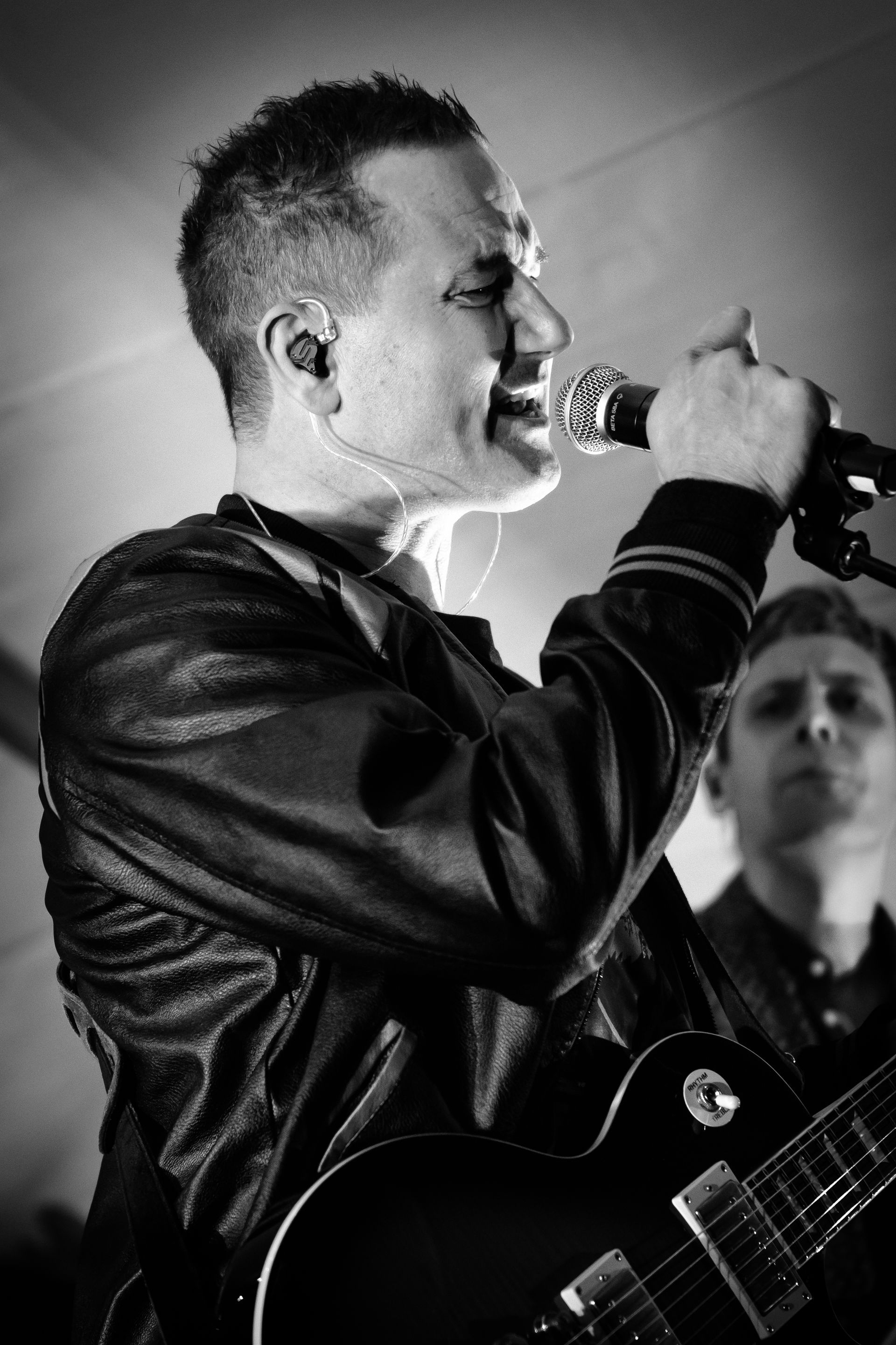 En mann synger i en mikrofon mens han holder en gitar.