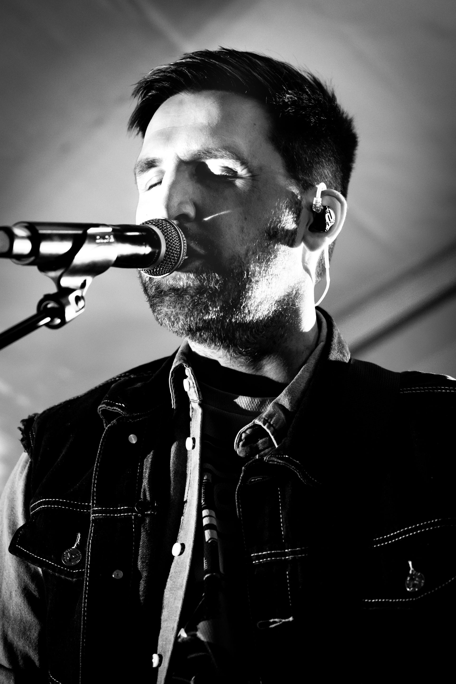 En mann synger i en mikrofon på et svart-hvitt-bilde.