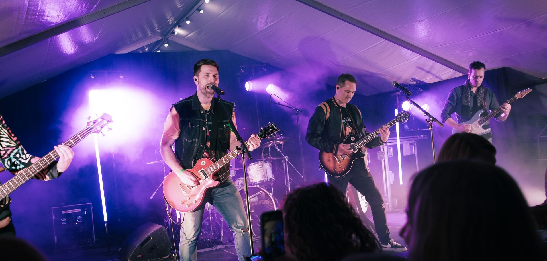 En gruppe menn spiller gitar på en scene foran en folkemengde.