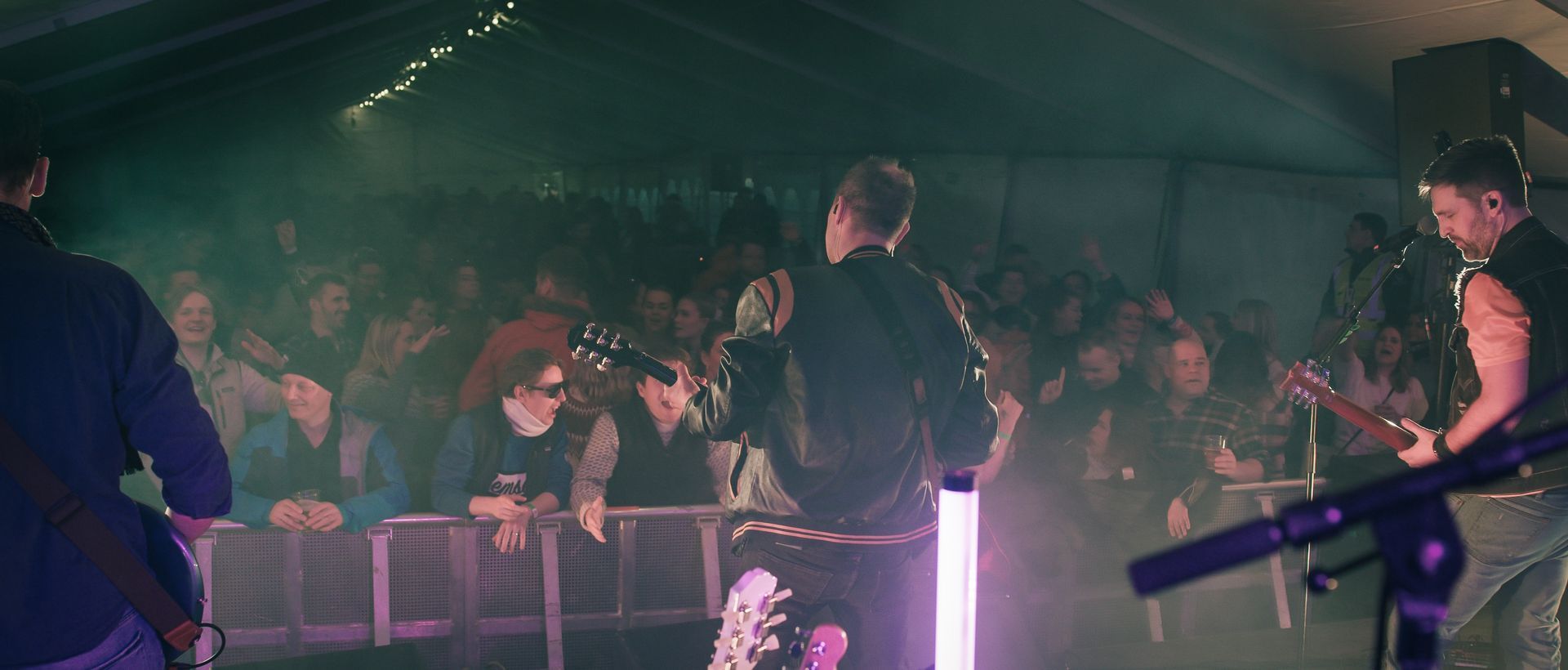 En gruppe menn spiller gitar på en scene foran en folkemengde.
