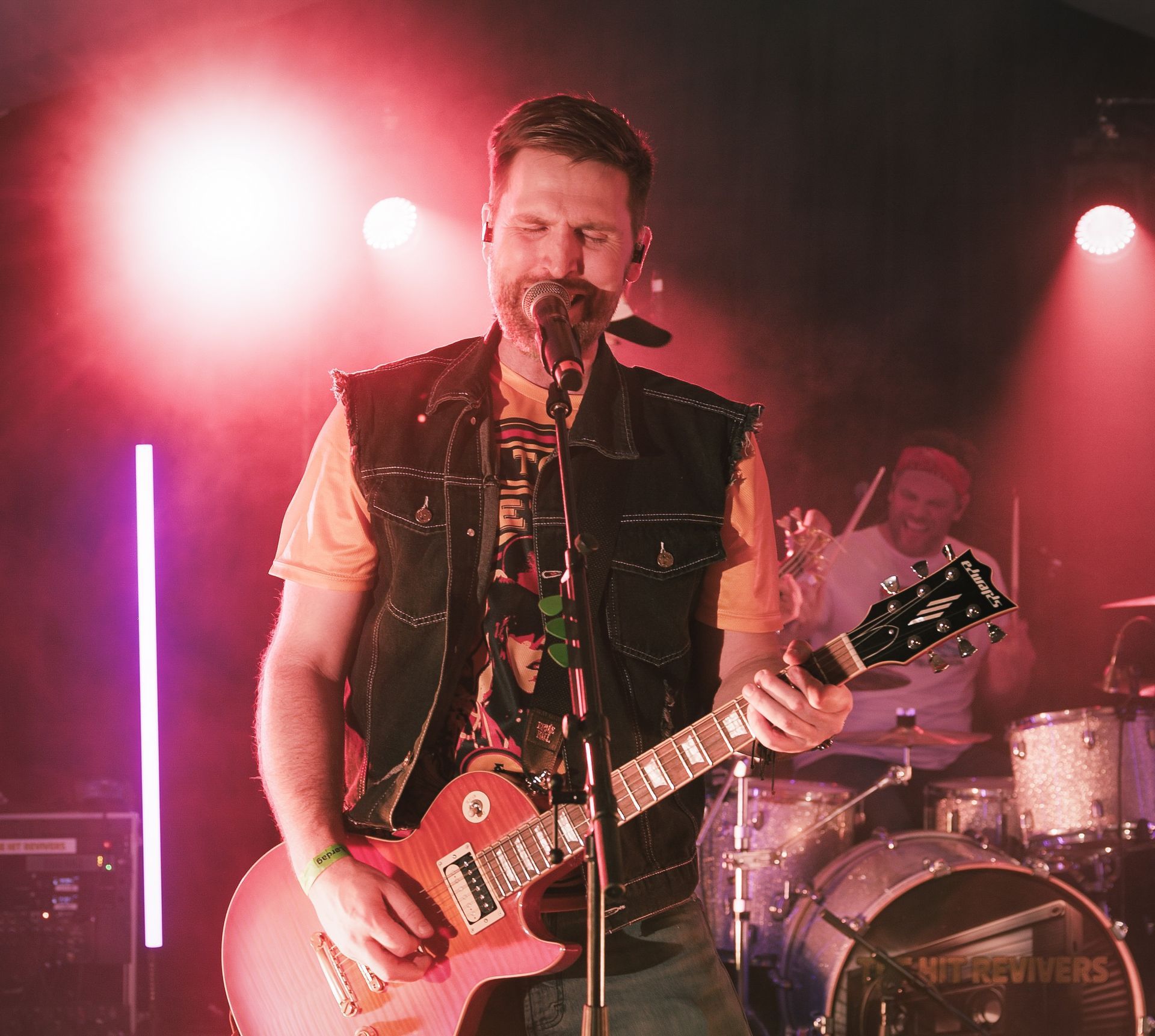 En mann som synger i en mikrofon mens han spiller gitar