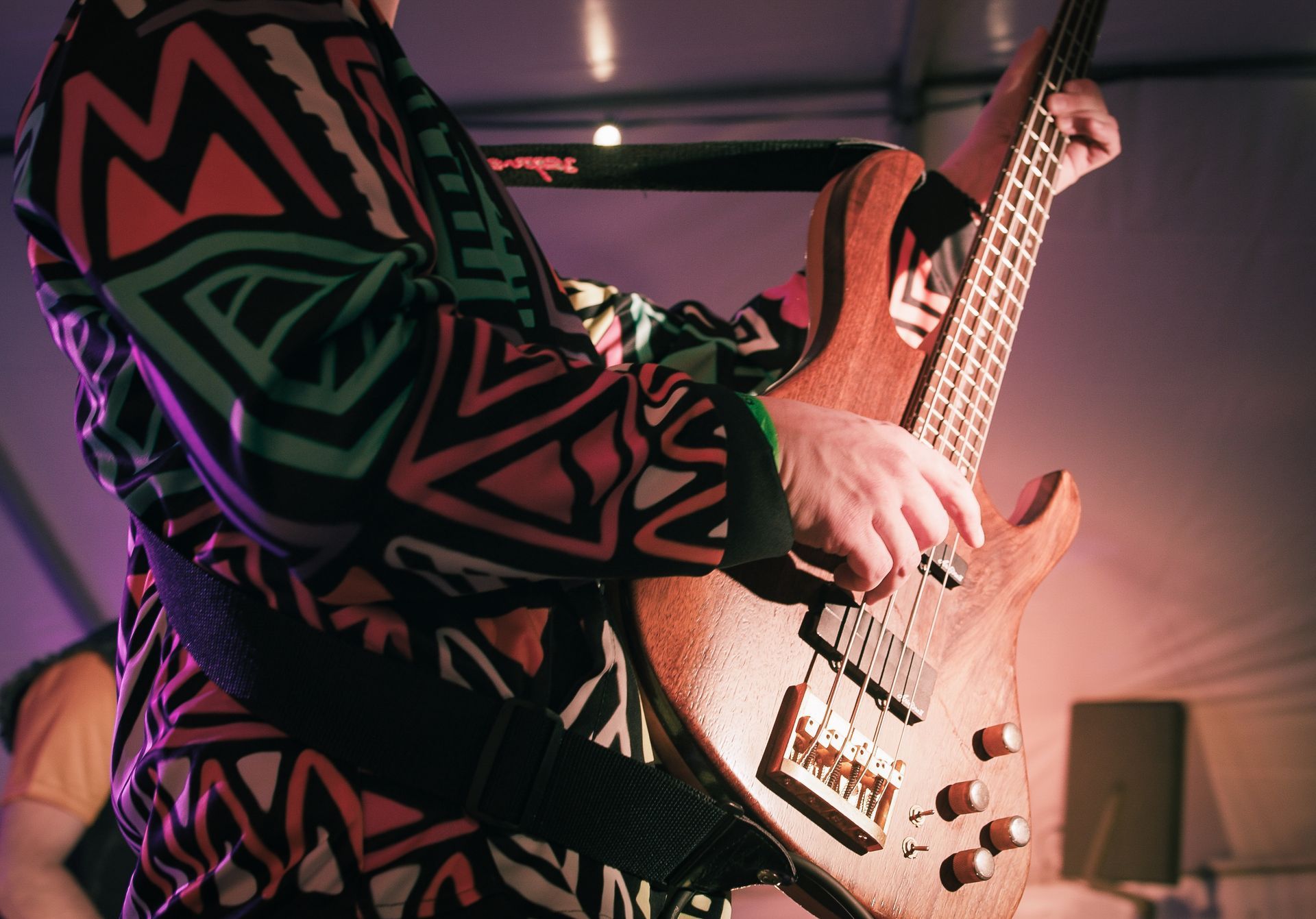 En mann i en fargerik skjorte spiller en bassgitar.