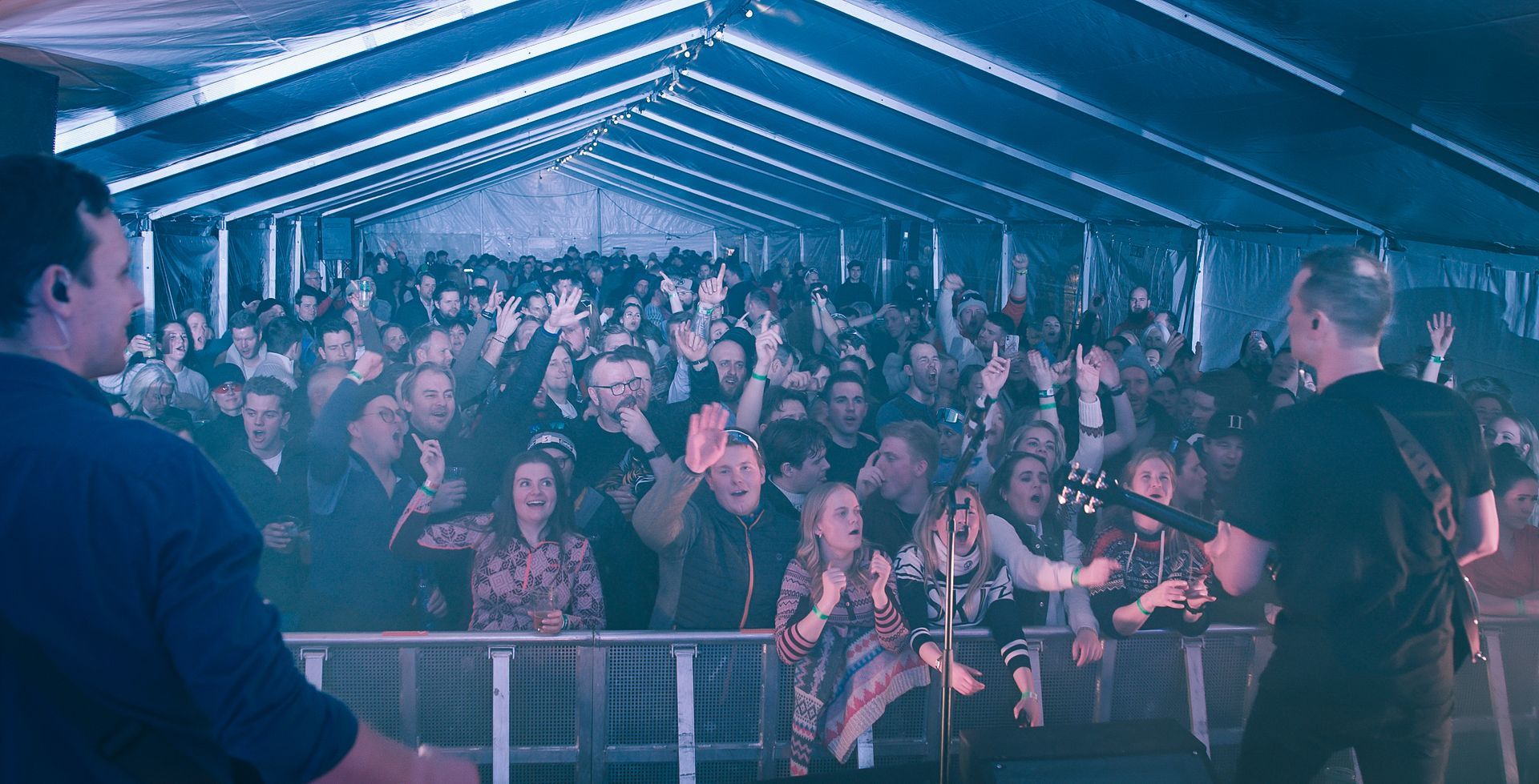 En mann spiller gitar foran en mengde mennesker på en konsert.