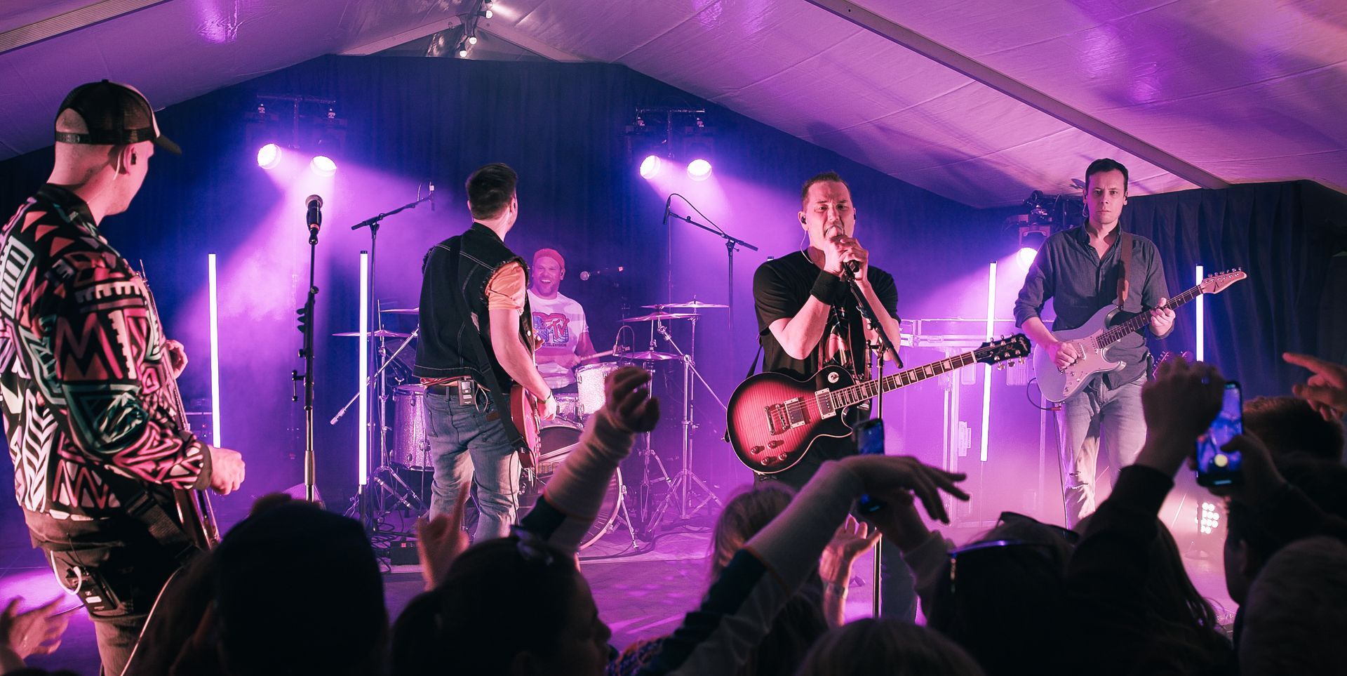 En gruppe menn spiller instrumenter på en scene foran en folkemengde.