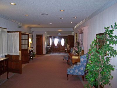 The front door of a house with a porch and plants in front of it.