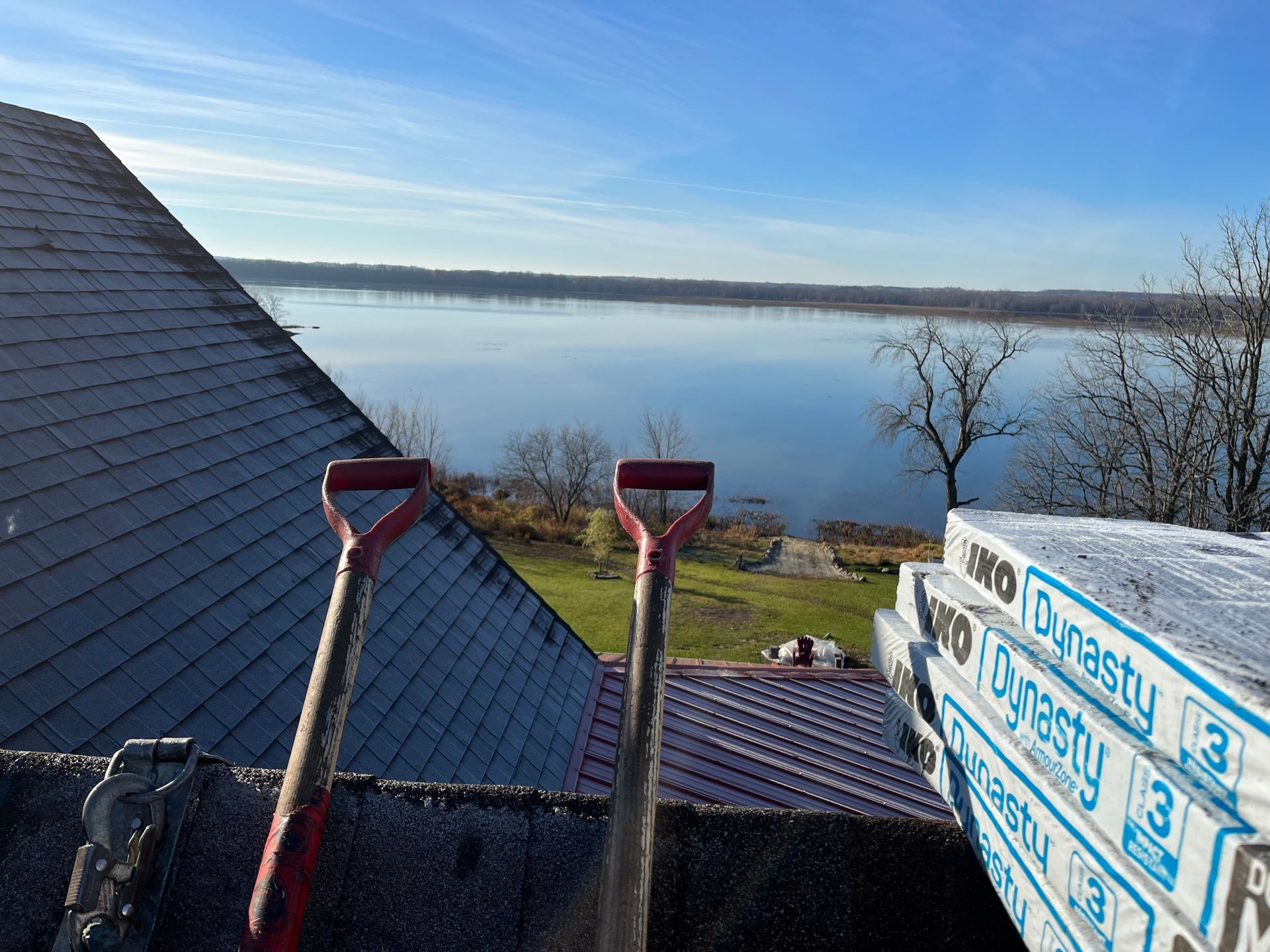 Deux pelles sont posées au sommet d'un toit surplombant un lac.
