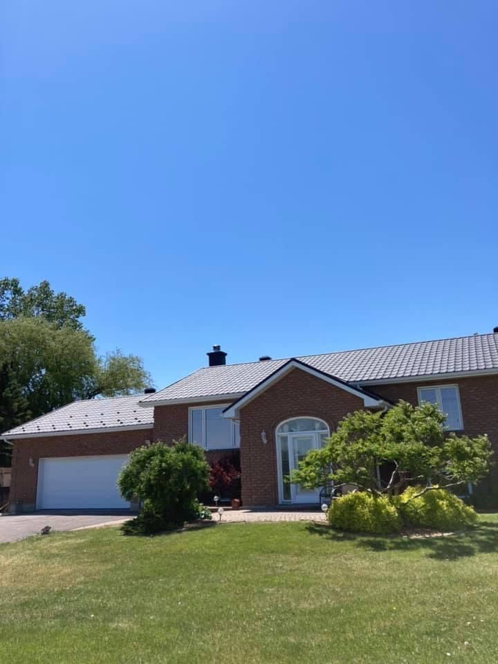 Une maison en brique avec un toit gris et un ciel bleu en arrière-plan.