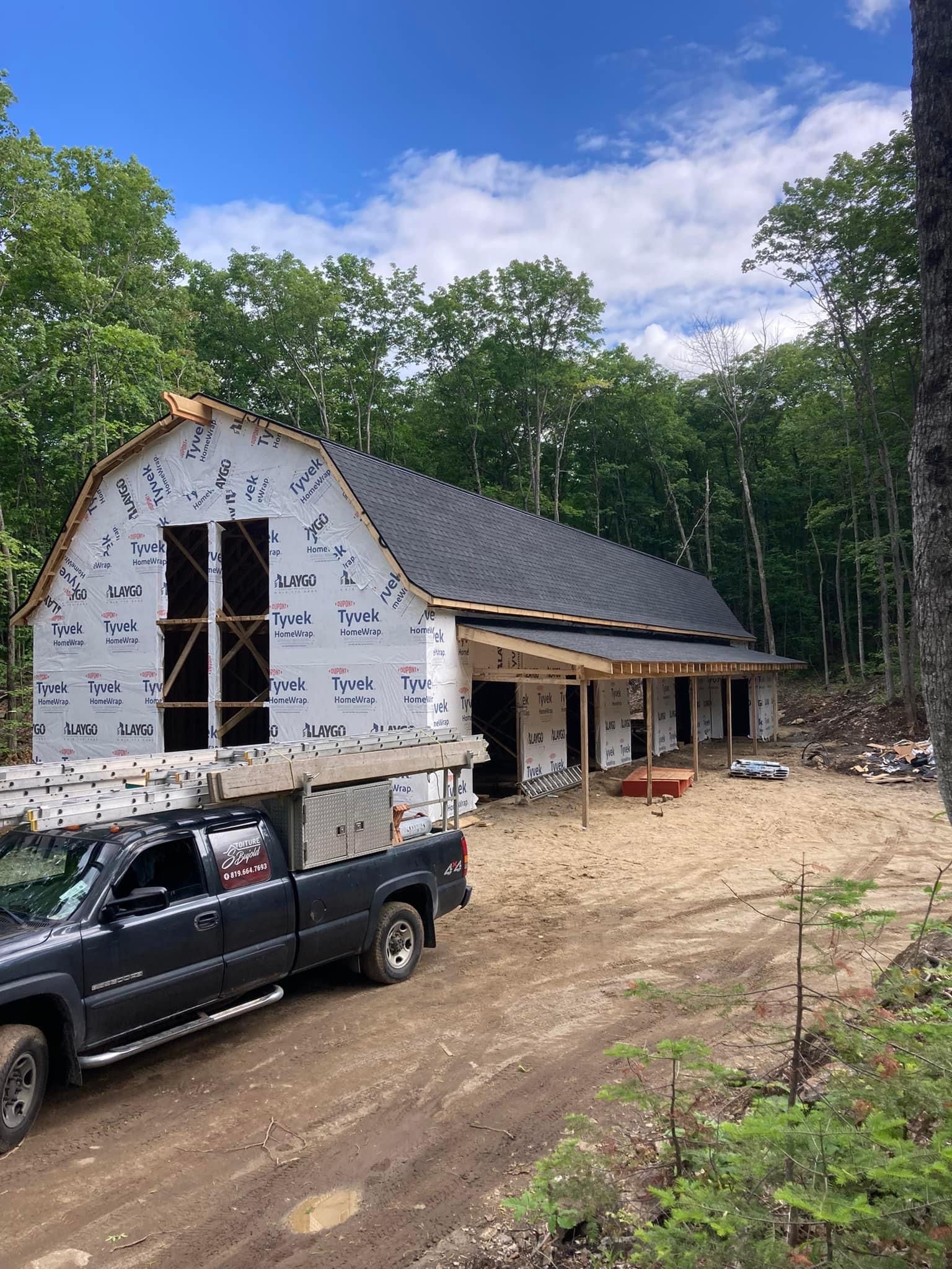 Un camion est garé devant une grange en construction.