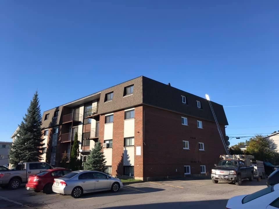 Un grand bâtiment en brique avec des voitures garées devant.